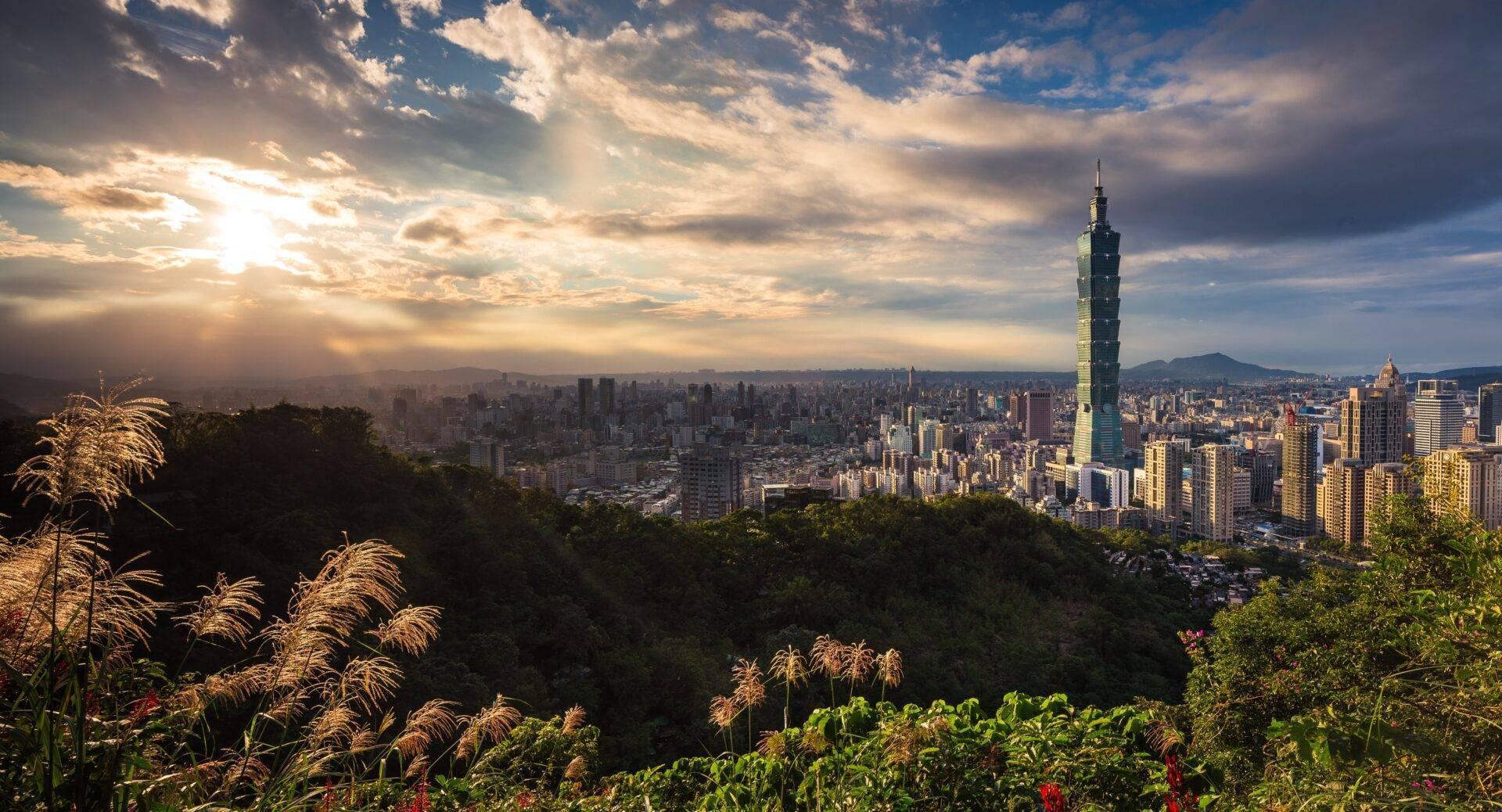 Vue panoramique d’une métropole asiatique densément construite avec une tour distinctive et montagnes en arrière-plan