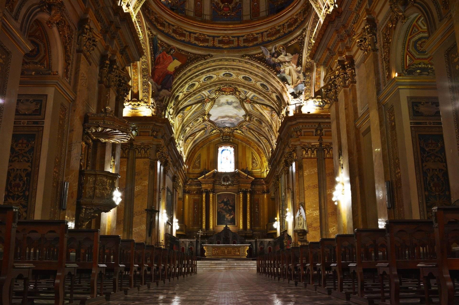 Intérieur majestueux d’une basilique avec nef centrale dorée, voûte ornementée et autel illuminé