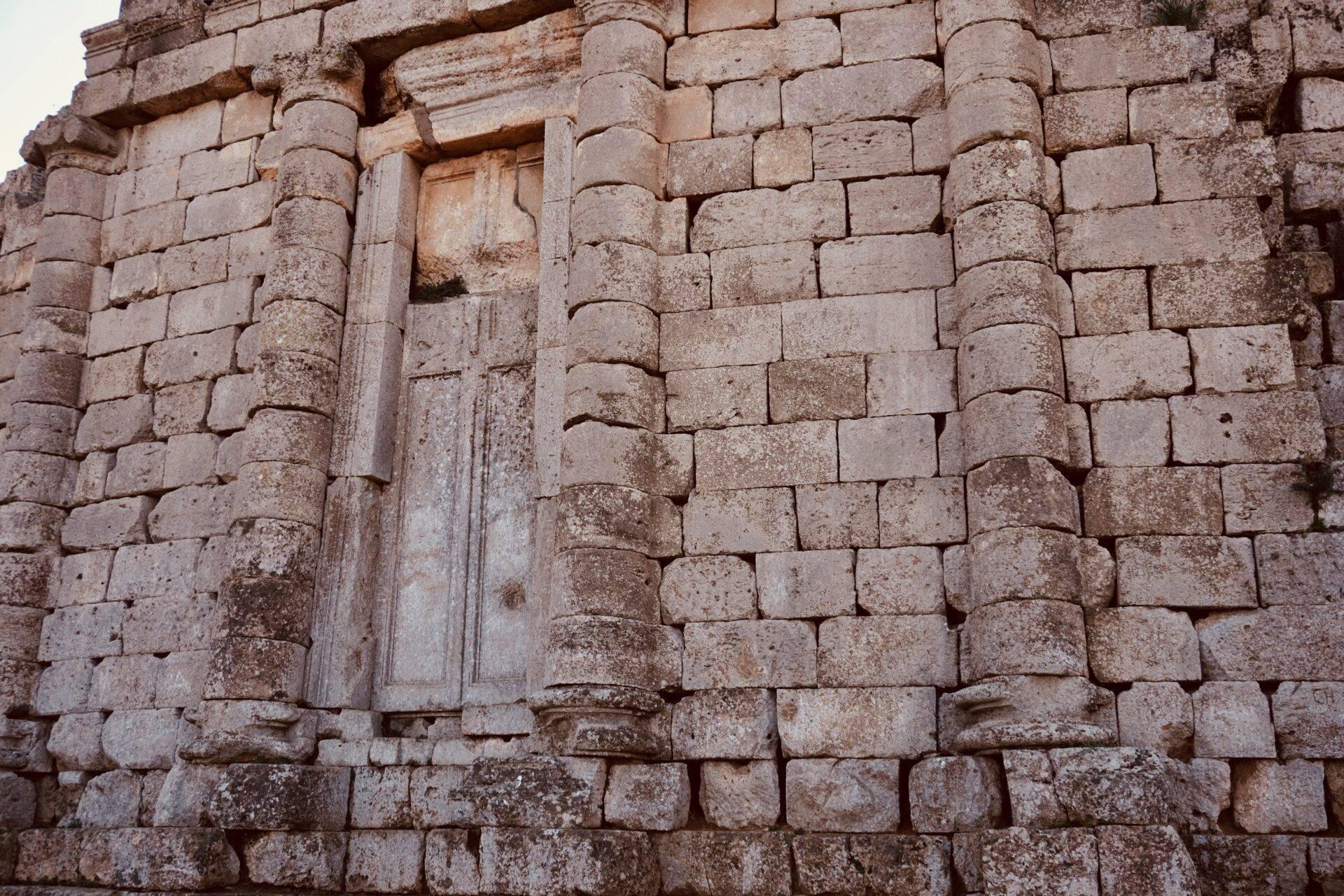 Détail d’une façade en pierre ancienne avec colonnes cylindriques et portal architecturé, témoignage d’architecture historique