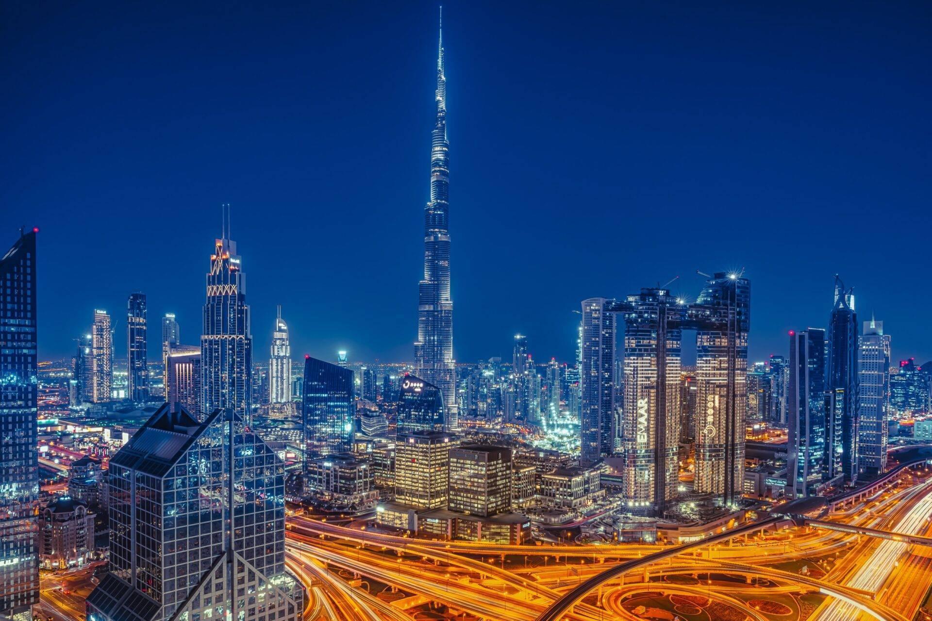 Vue nocturne d’une skyline urbaine avec gratte-ciel illuminés et autoroutes surélevées en premier plan