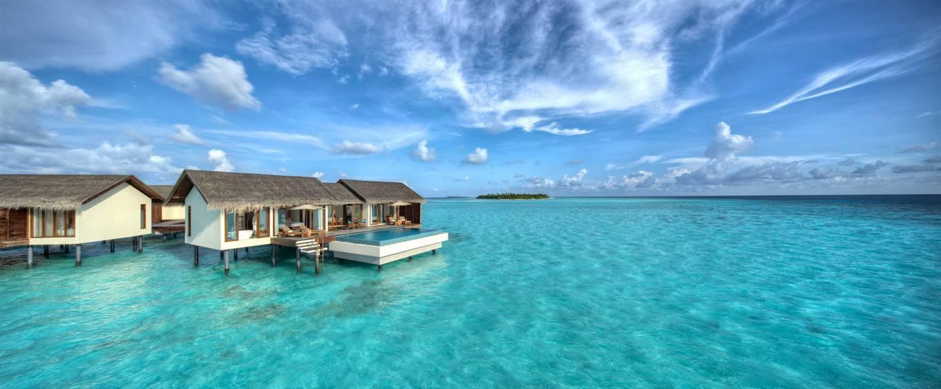Bungalows de luxe sur pilotis avec piscine dans une eau turquoise cristalline sous ciel bleu