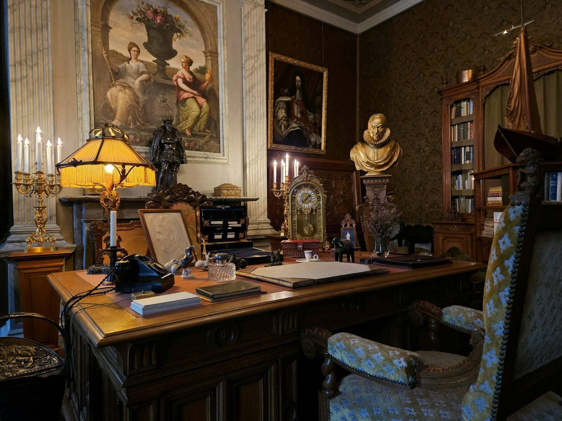 Un bureau historique richement meublé avec desk en bois, bustes, tableaux anciens et candélabres dorés