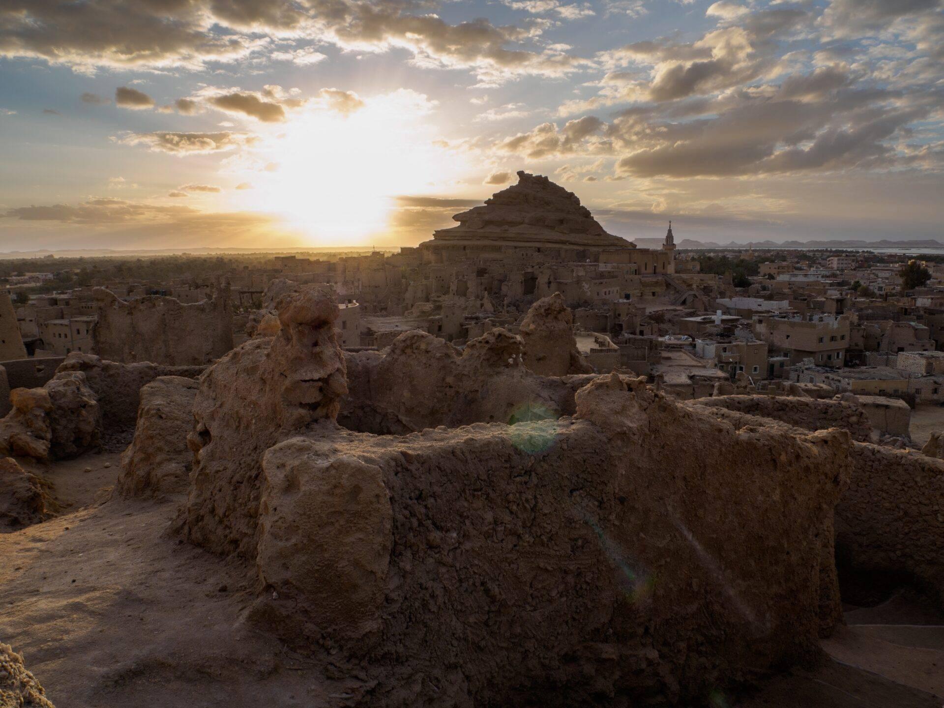 Vue panoramique d’une ancienne citadelle en pierre au coucher de soleil dominant un village désertique en Égypte
