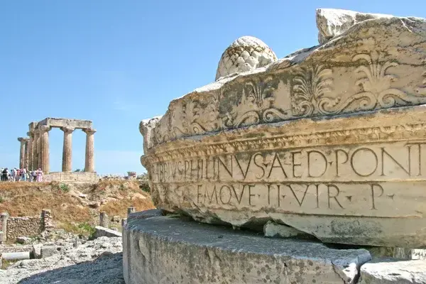 Ruines antiques avec colonnes corinthiennes et inscription latine gravée sur pierre calcaire érodée