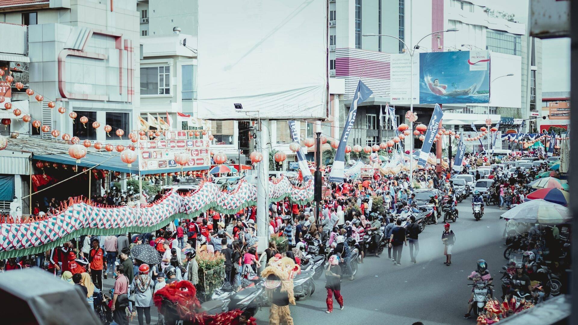 Une rue urbaine bondée décorée de lanternes rouges et de drapeaux lors d’une célébration festive en Indonésie