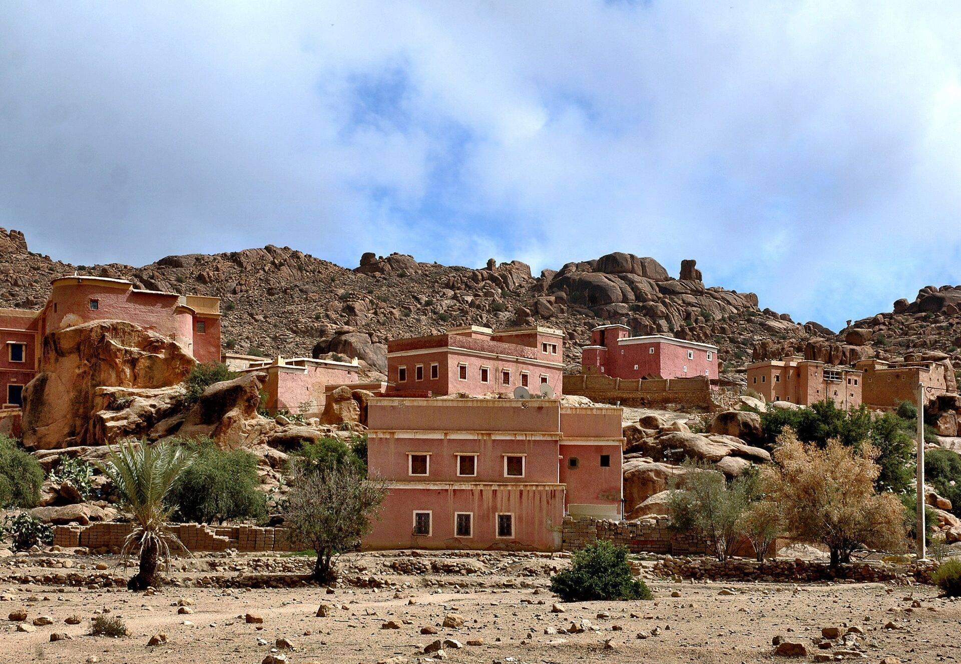 Village berbère aux maisons en terre ocre blotti contre des rochers granitiques dans un paysage désertique aride