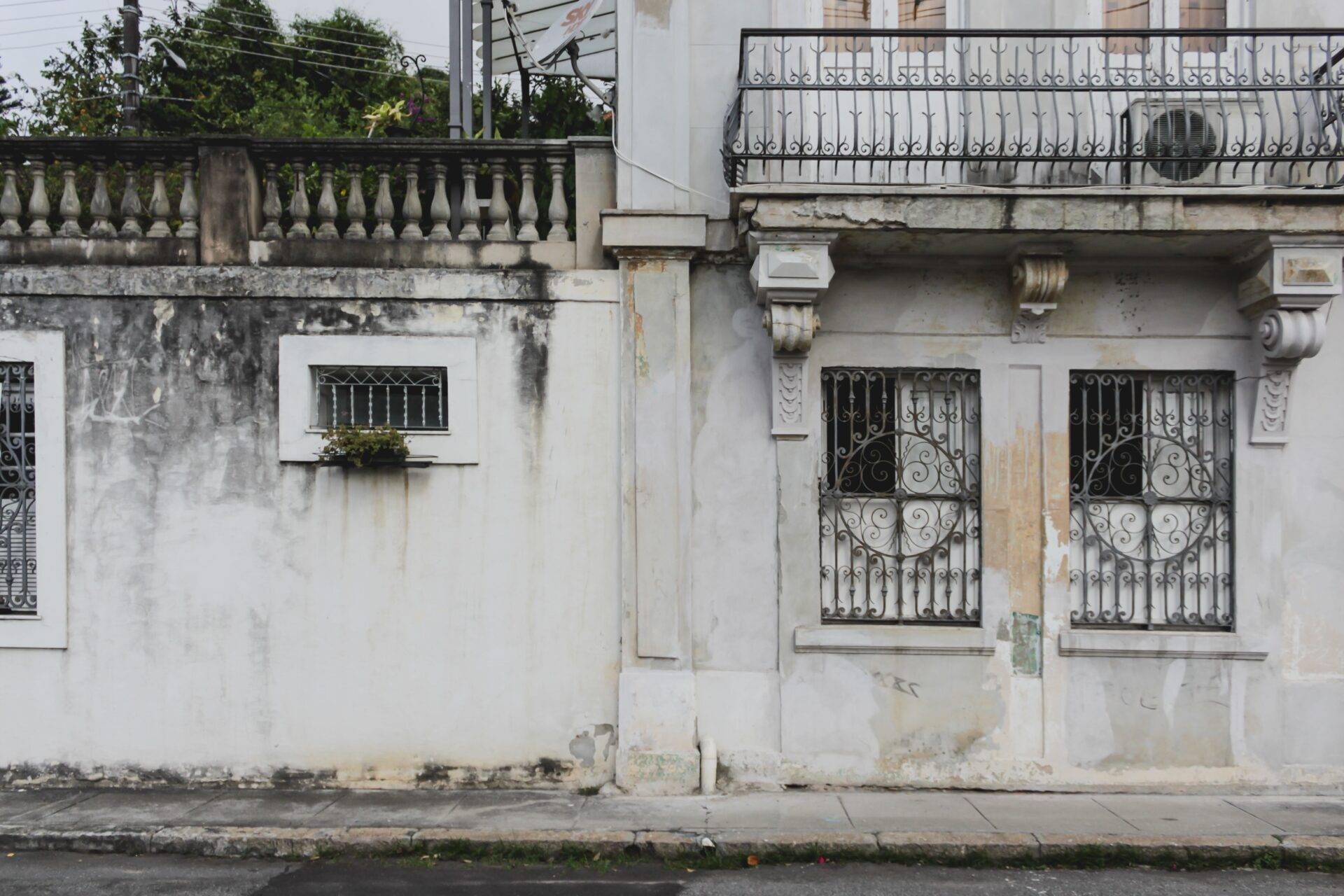 Façade coloniale décrépite avec balcon en fer forgé et portes ornementales dans une rue pavée d’une ville historique brésilienne