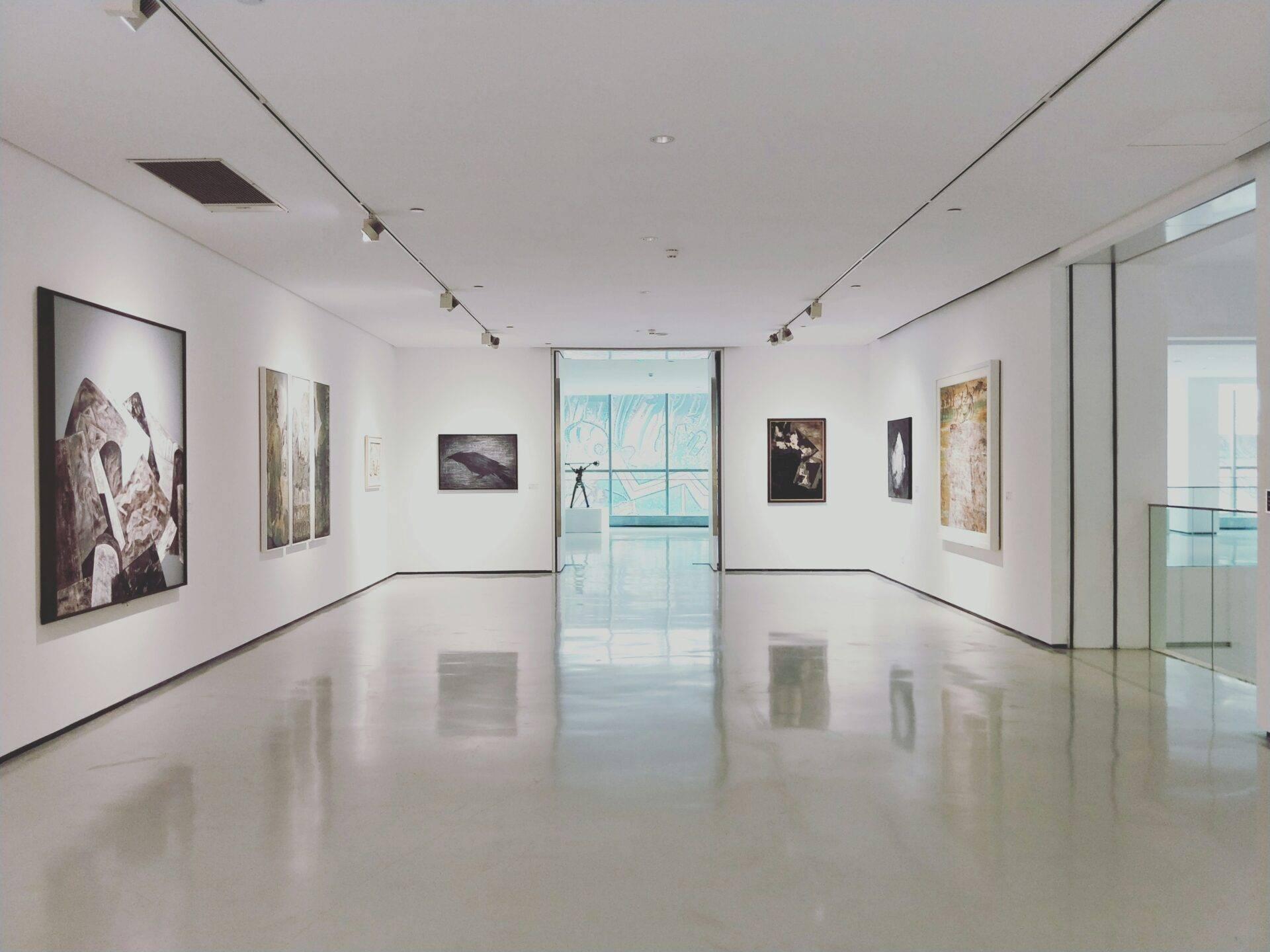 Galerie d’art moderne avec exposition photographique, plafond blanc minimaliste et sol brillant reflétant les œuvres