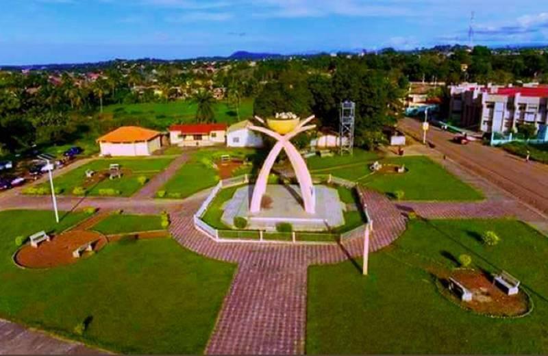 Vue aérienne d’une place publique avec monument central en arc, bâtiments colorés et espaces verts en Guinée