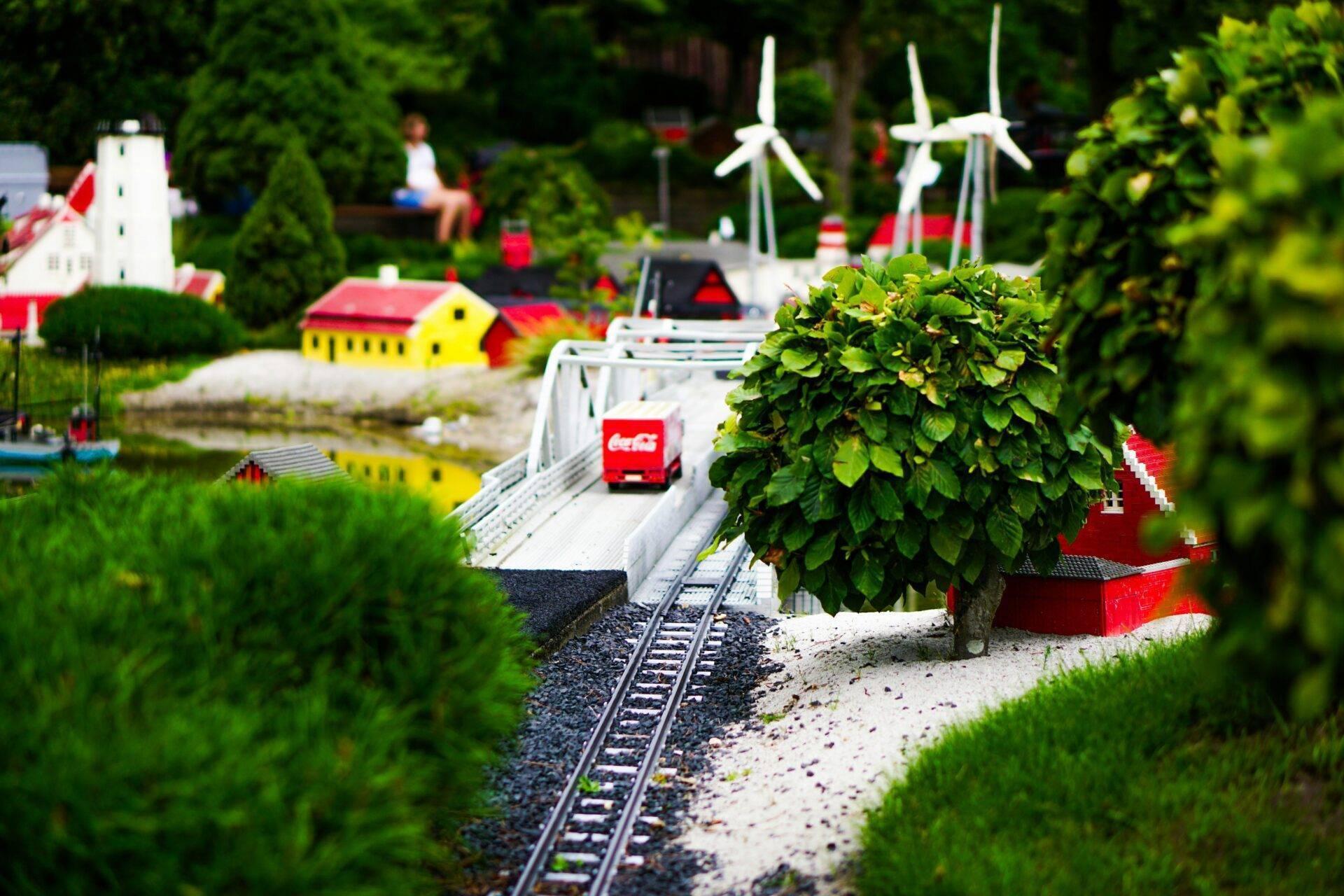 Miniature d’un village danois avec train rouge, maisons colorées, éoliennes blanches et verdure luxuriante
