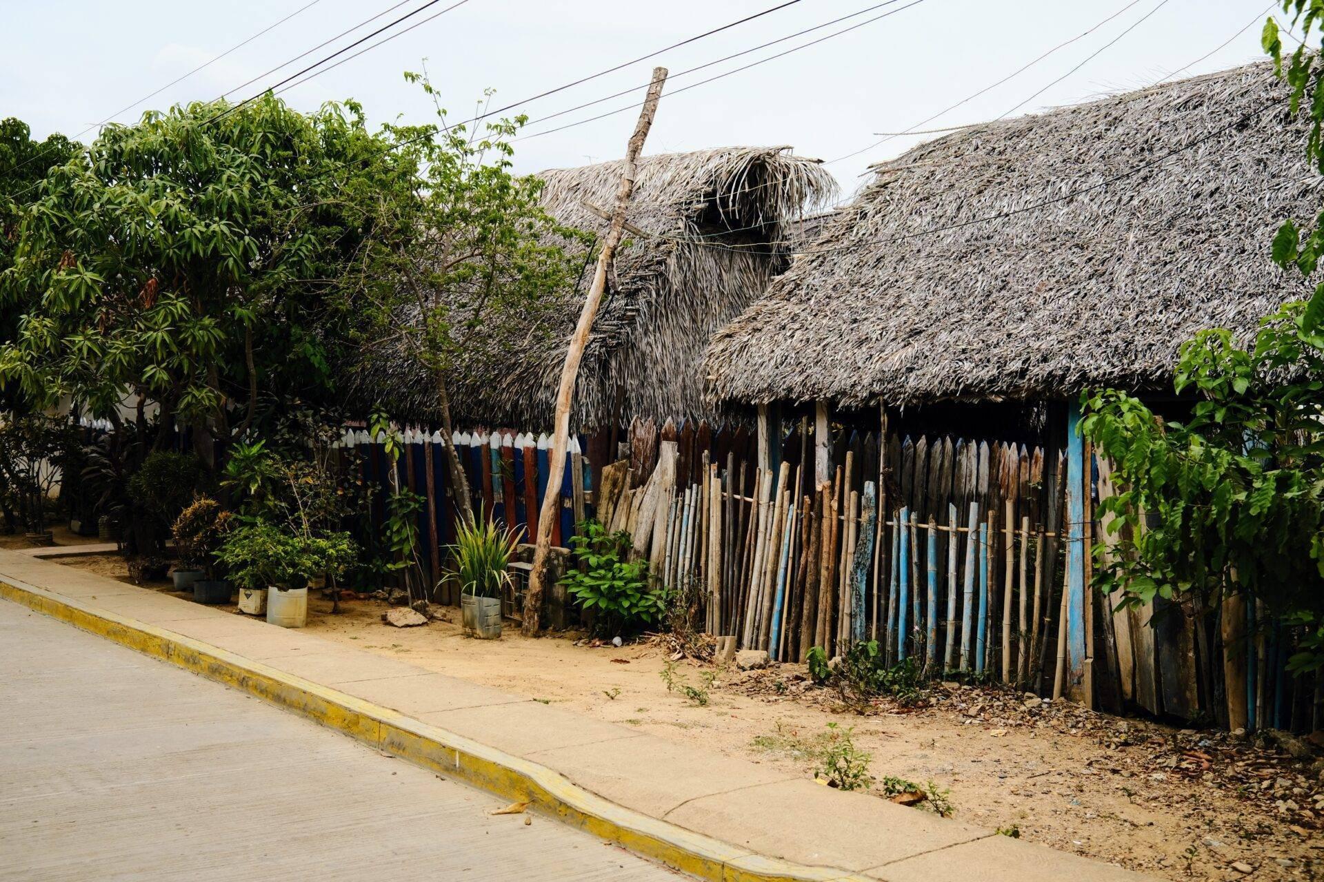 Maison traditionnelle aux murs de chaume et palissade en bois dans un village côtier colombien