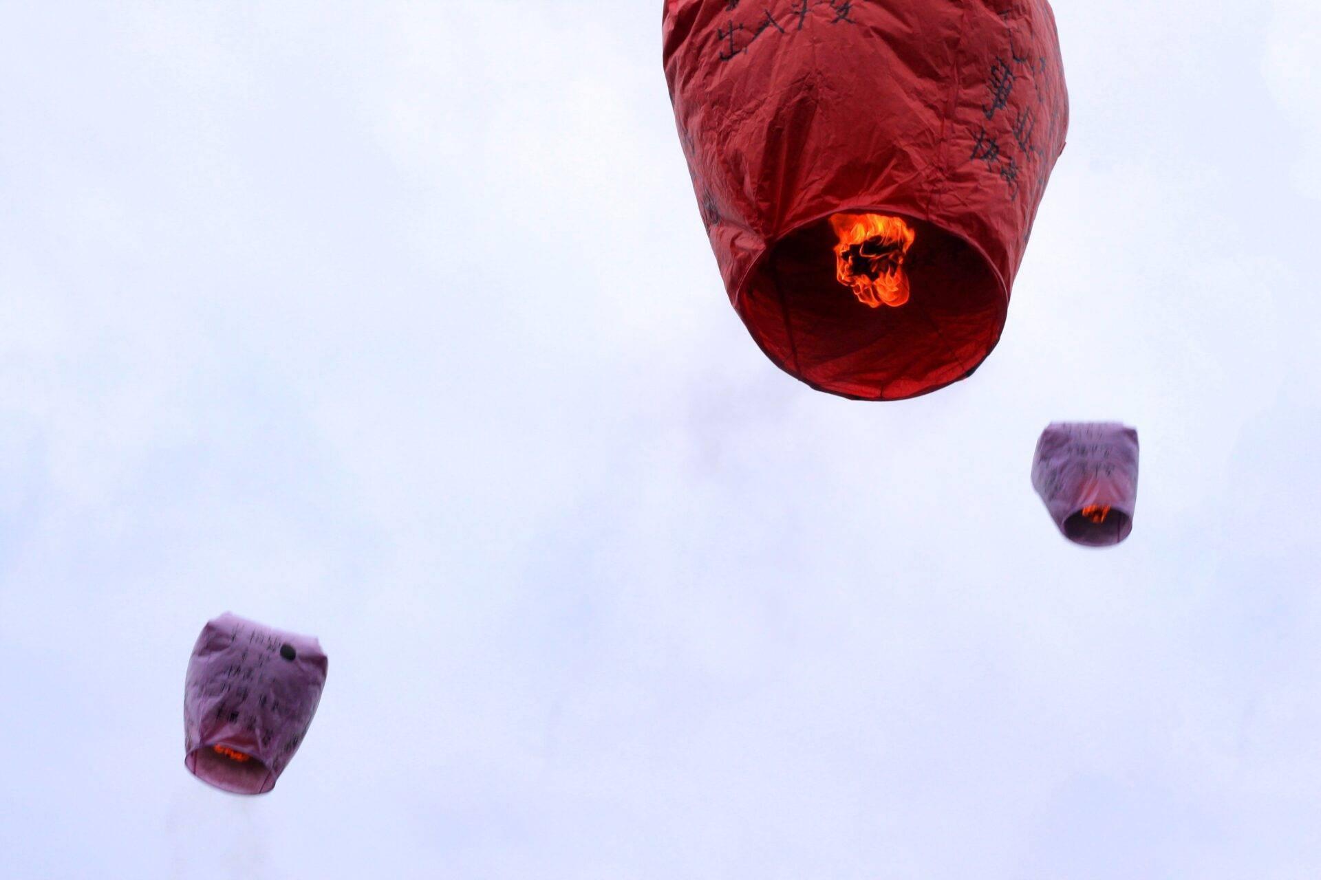 Lanternes volantes rouges et violettes s’envolant dans le ciel crépusculaire lors d’une célébration traditionnelle