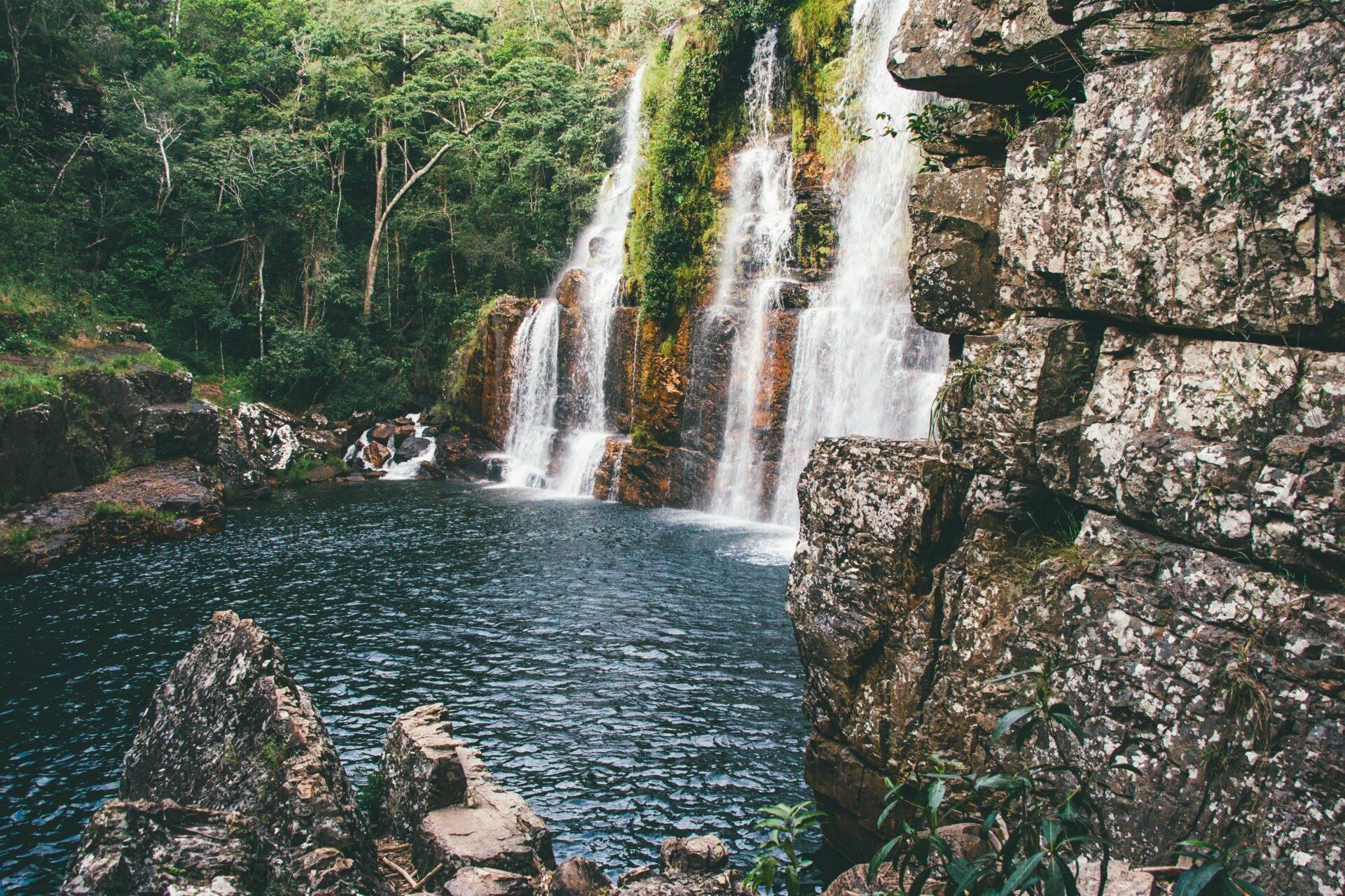 Cascades spectaculaires tombant dans un bassin turquoise entouré de falaises rocheuses et de jungle luxuriante