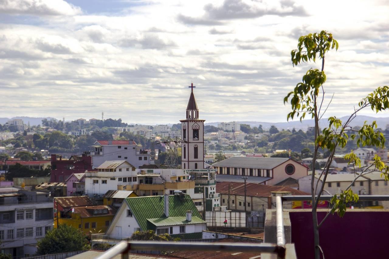 Vue panoramique d’une ville avec église à clocher blanc dominant les toits colorés et paysage montagneux