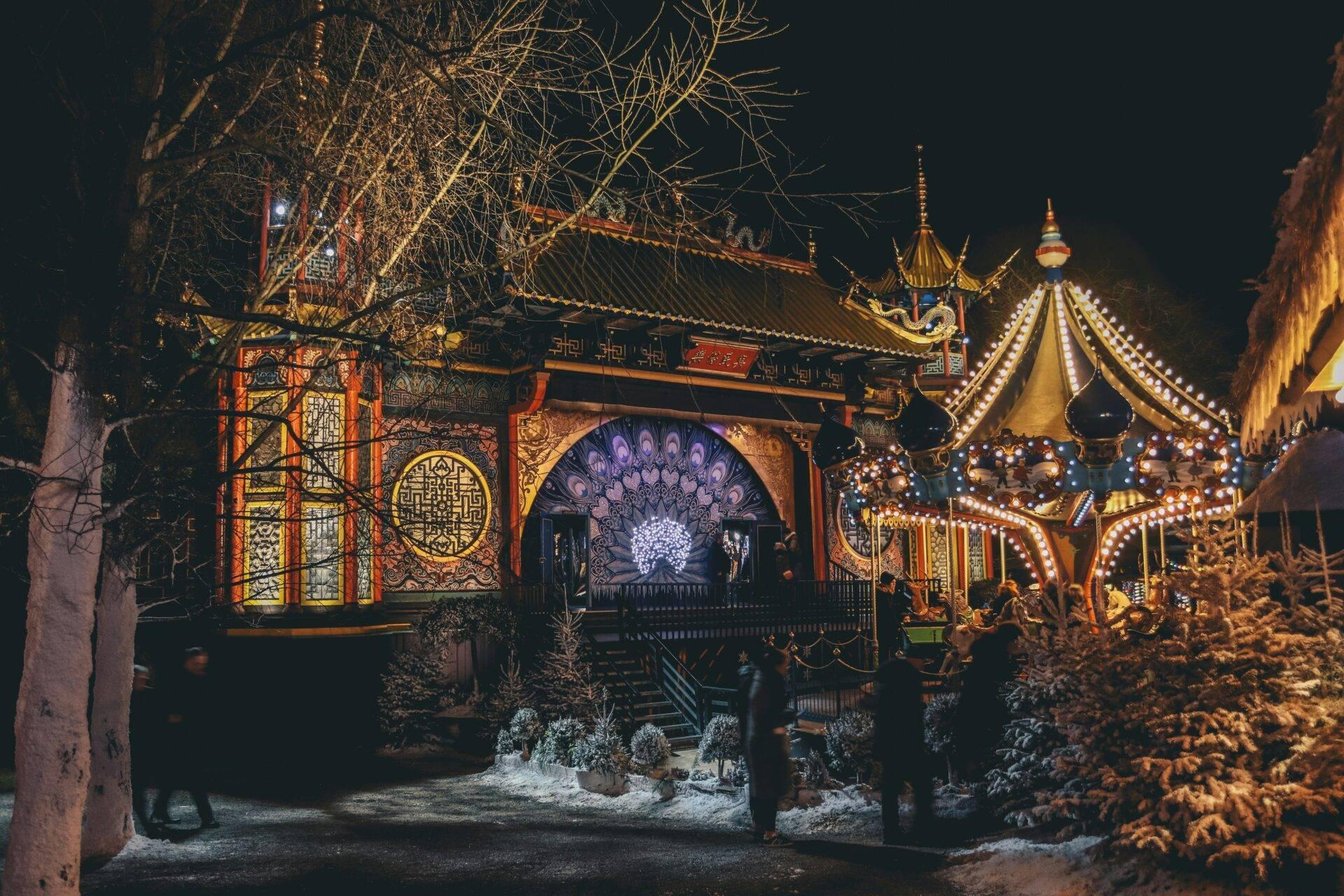Vue nocturne d’un parc d’attractions asiatique illuminé avec pagodes dorées et décorationslumin euses festives