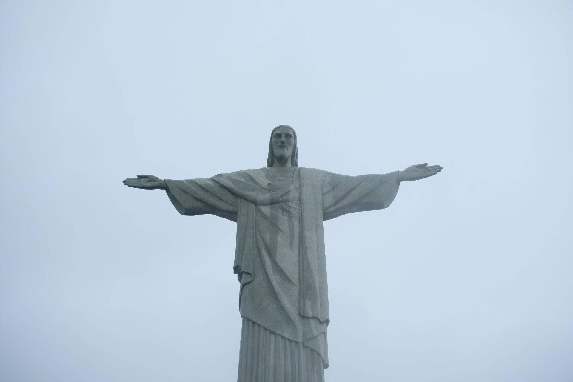 Statue colossale aux bras écartés dominant un paysage sous ciel dégagé, monument emblématique brésilien