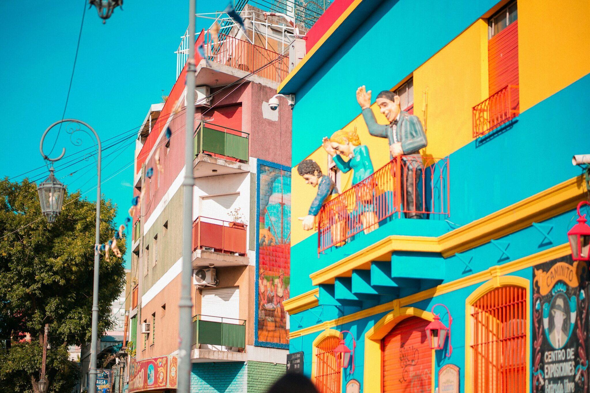Façade colorée avec bâtiments jaunes, bleus et rouges ornés de murales représentant des enfants jouant