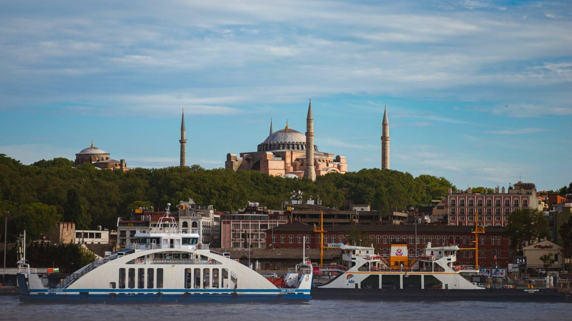 Deux navires de croisière devant une mosquée majeure aux dômes et minarets dominant une ville historique en bord de mer