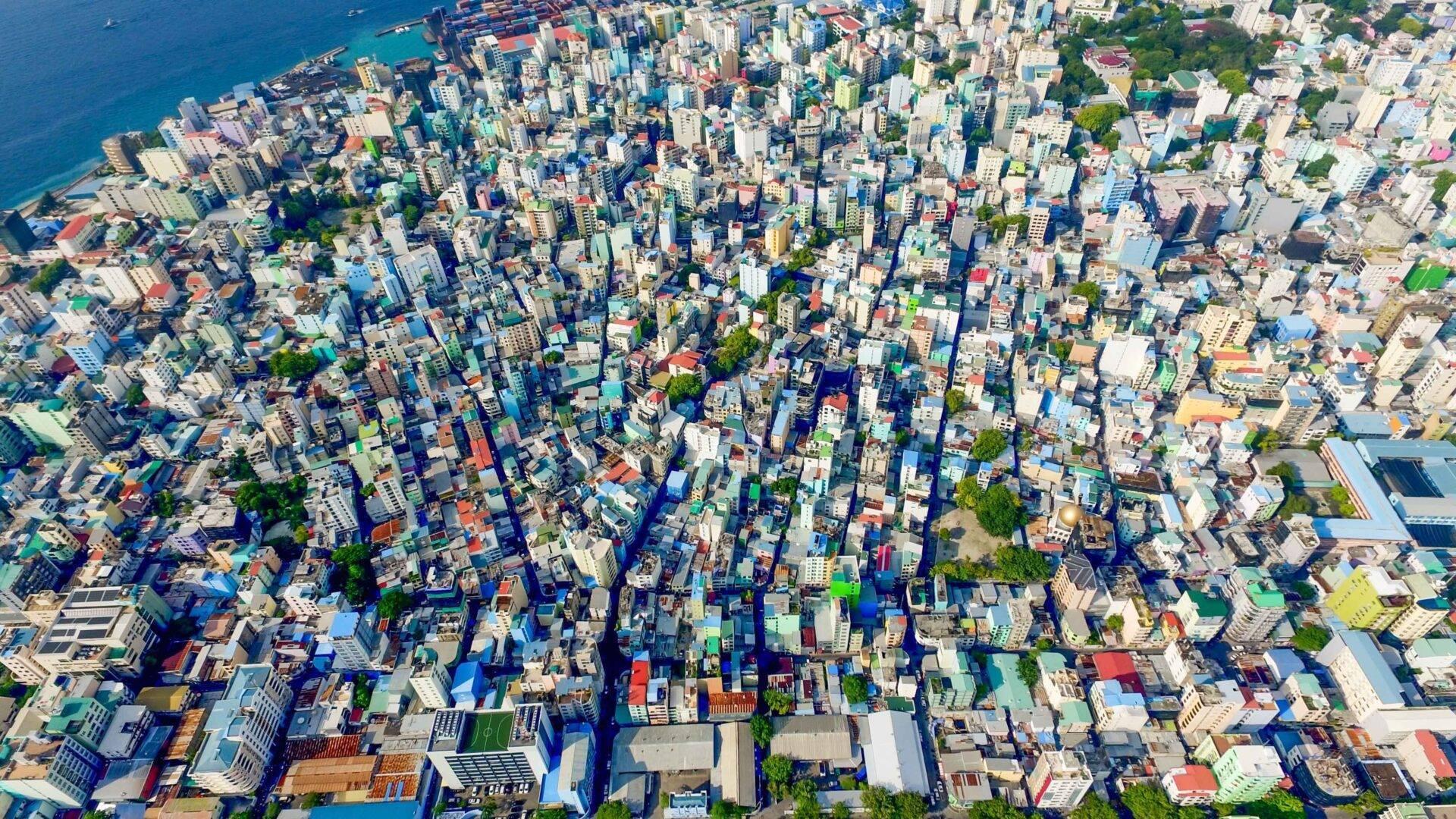 Vue aérienne d’une ville côtière densément construite avec immeubles colorés et mer turquoise en arrière-plan
