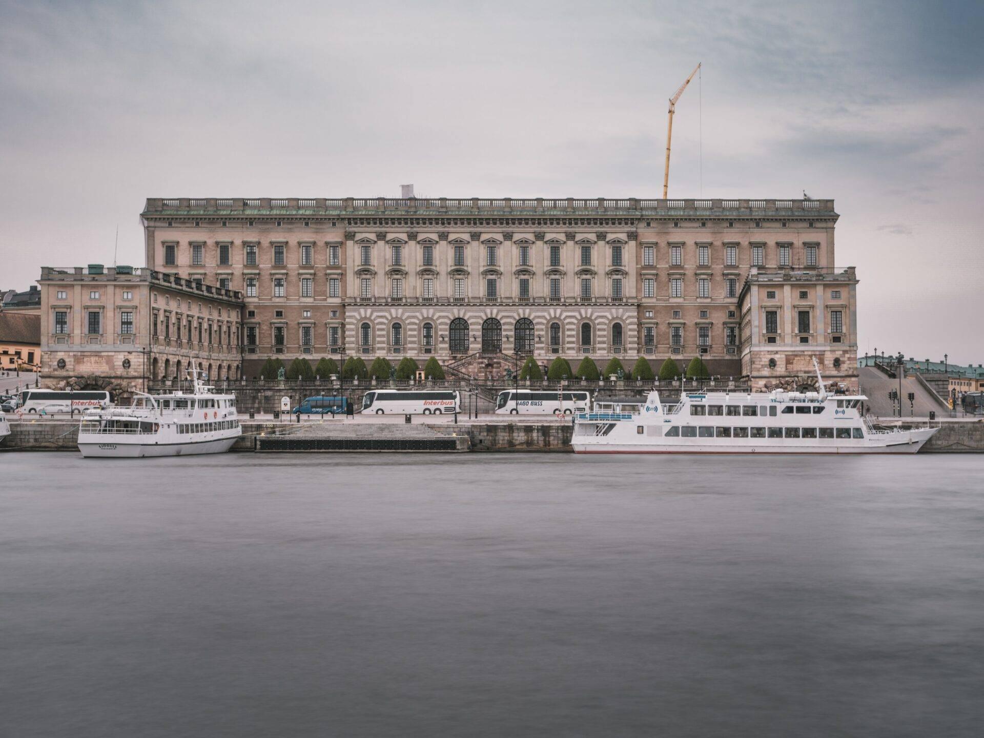 Palais royal rose au bord d’une eau calme avec deux bateaux de tourisme amarrés à proximité