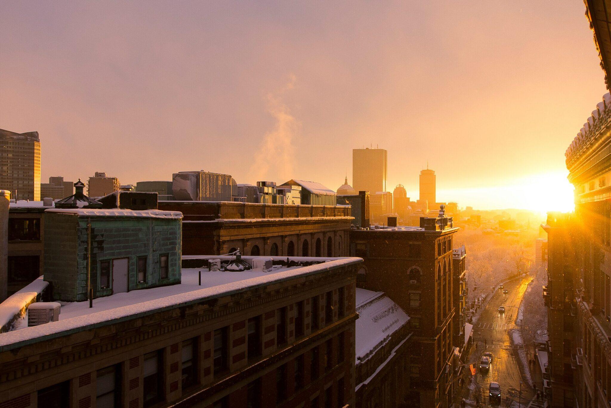 Vue aérienne d’une ville enneigée au coucher de soleil avec immeubles historiques et gratte-ciel modernes en arrière-plan