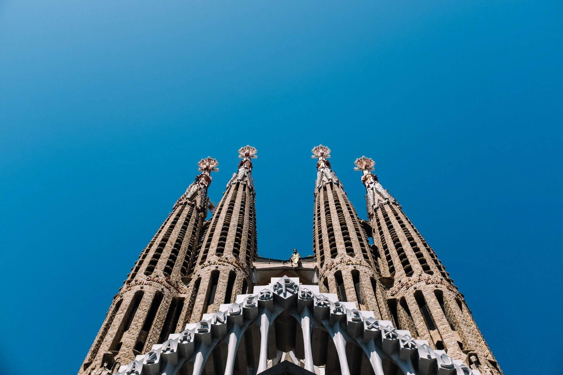Vue en contre-plongée de quatre tours pointues gothiques ornées de détails architecturaux sous ciel bleu dégagé