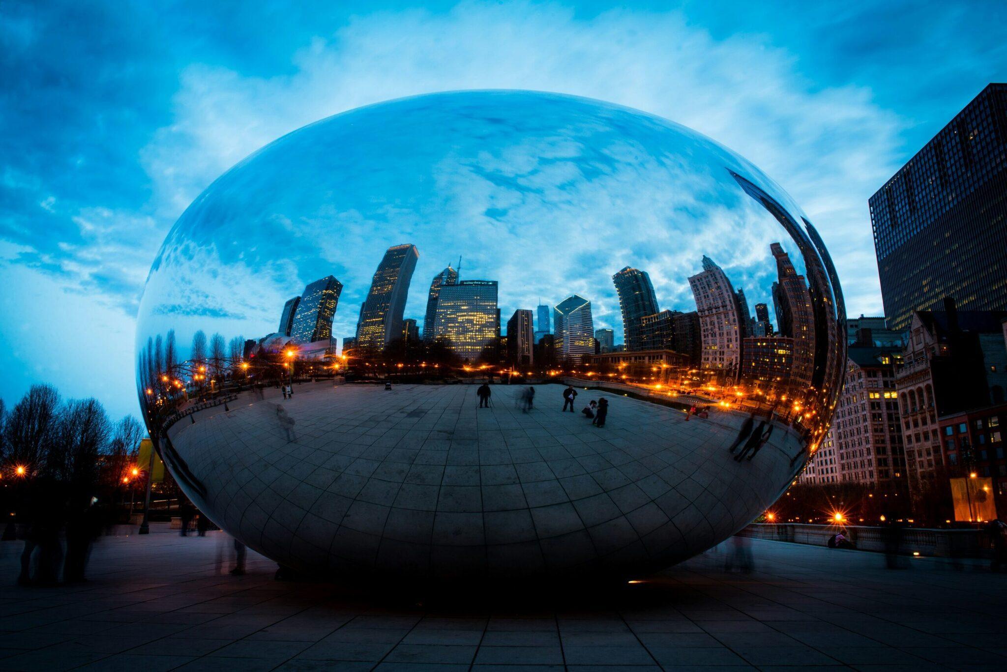 Une immense sculpture en acier poli reflétant le skyline d’une grande métropole moderne au crépuscule