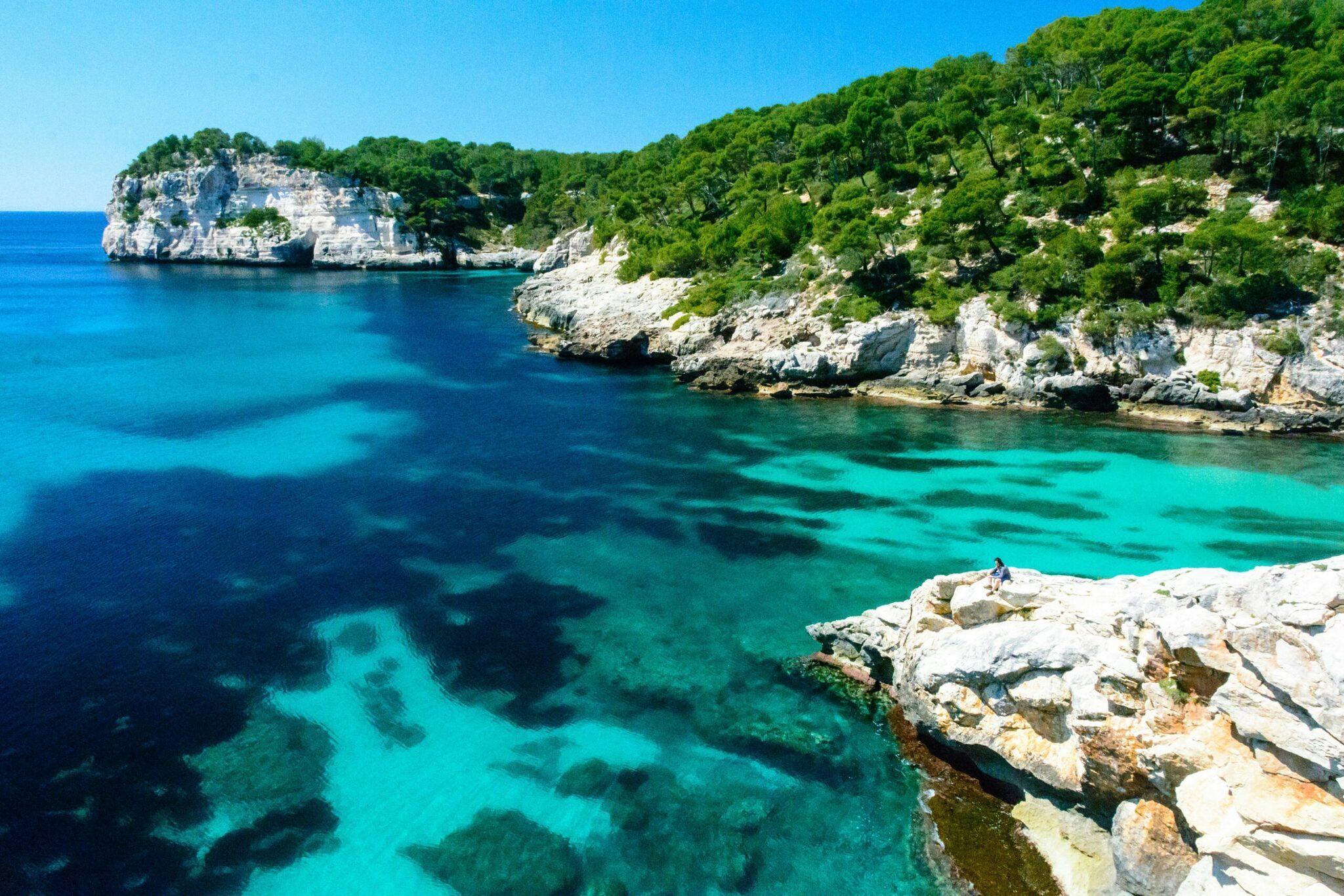 Une crique méditerranéenne aux eaux turquoise cristallines bordée de falaises calcaires et de végétation luxuriante