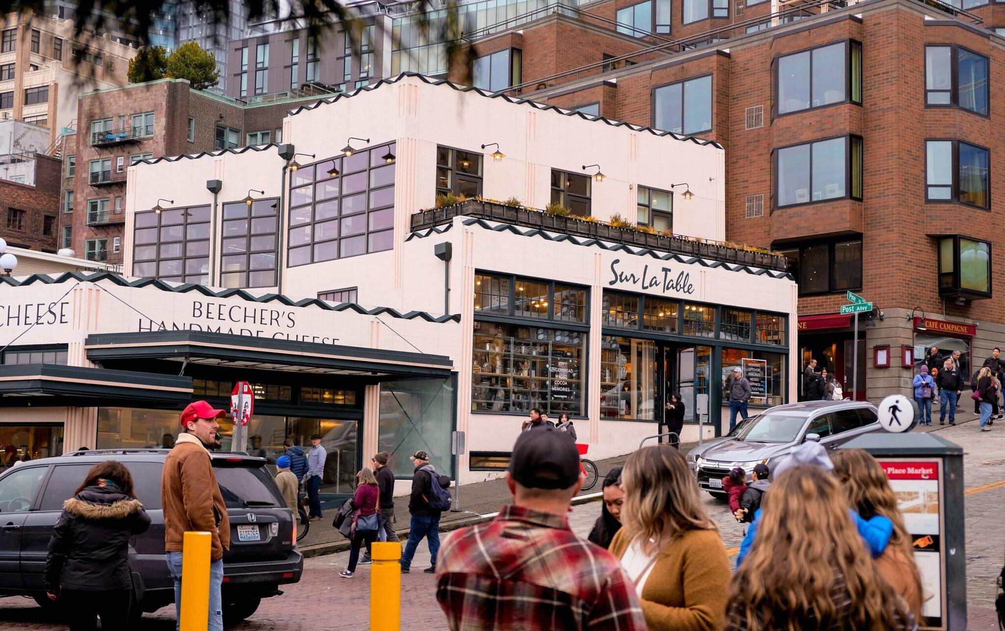 Une rue commerçante animée avec boutiques de fromage artisanal et restaurants, bâtiments en brique rouge, passants et véhicules