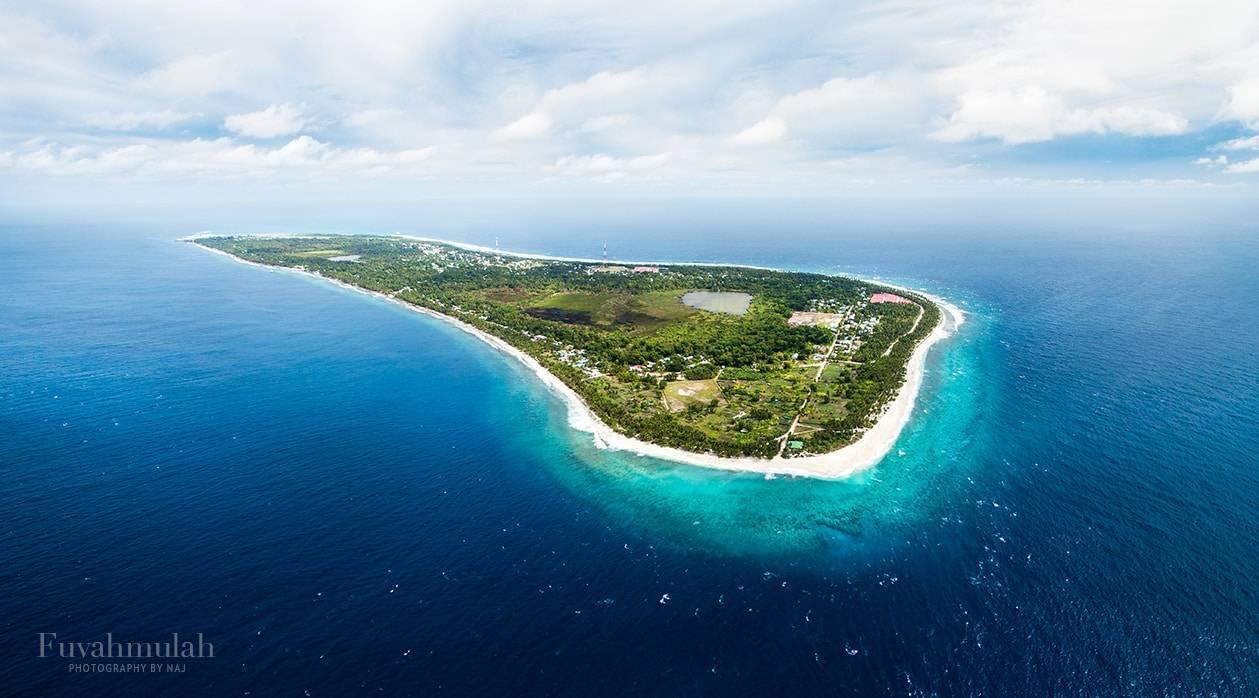 Vue aérienne d’une île tropicale entourée de récifs de corail turquoise et de plages blanches immaculées