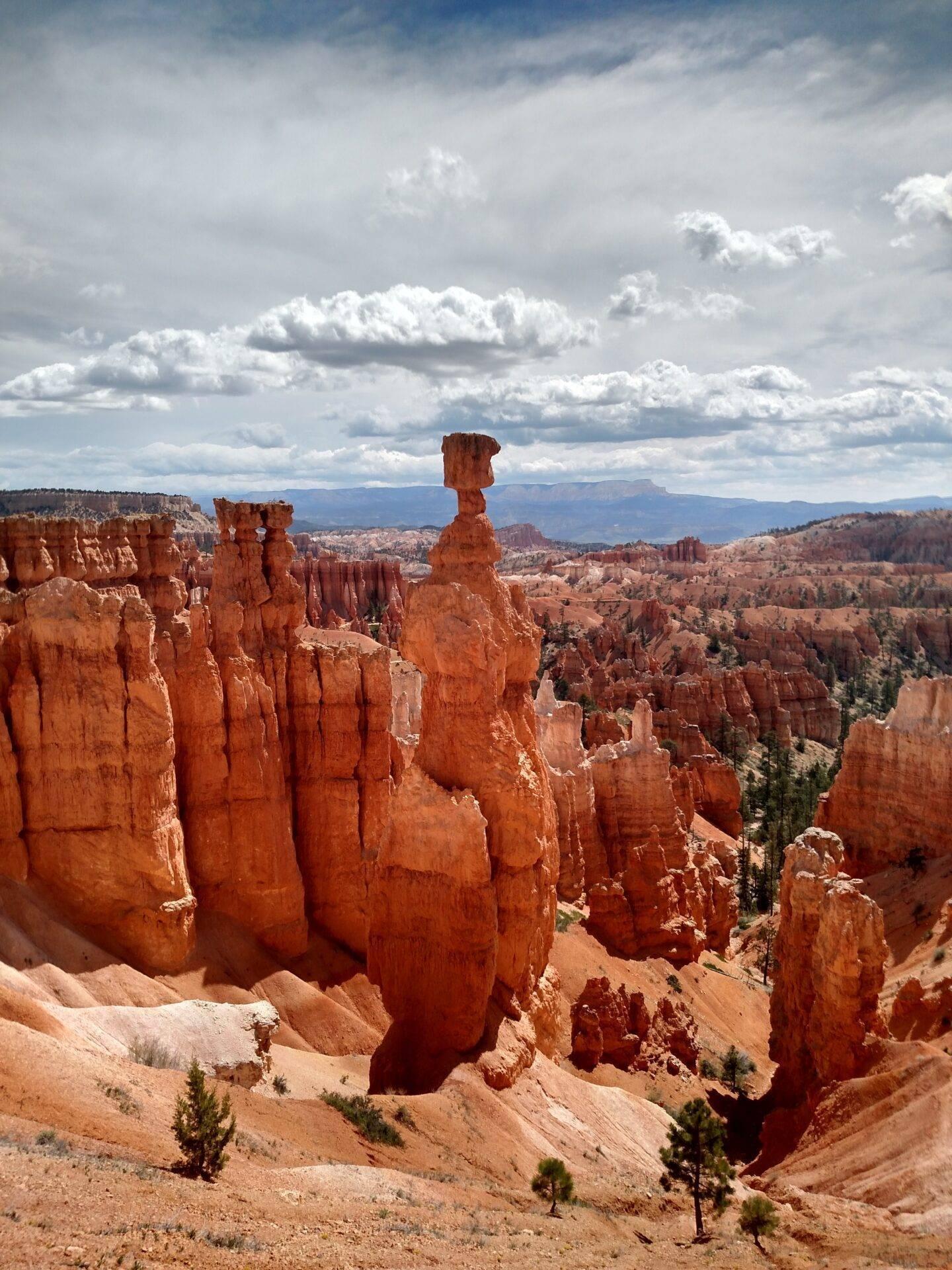 Formations rocheuses rouges spectaculaires et hoodoos dans un amphithéâtre naturel désertique sous ciel nuageux
