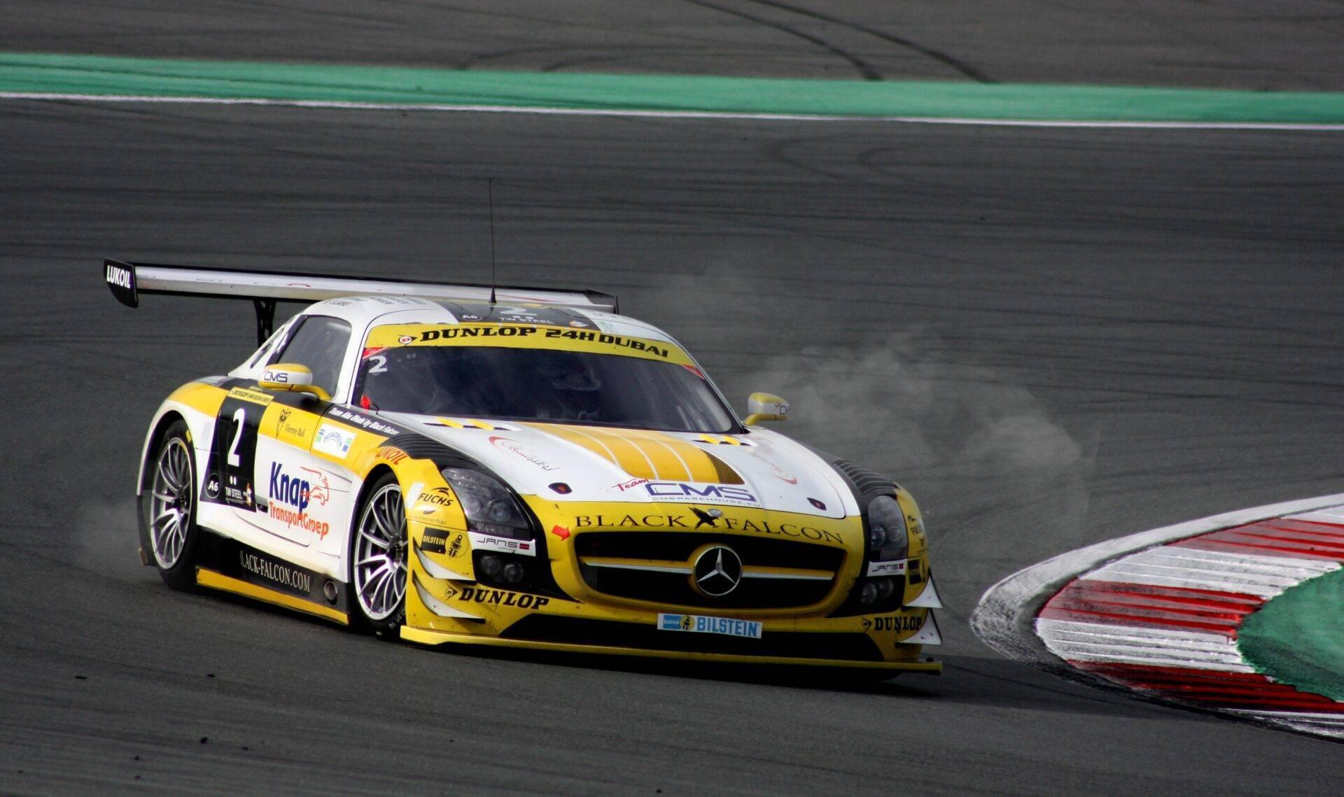 Voiture de course jaune et blanche sur un circuit automobile avec virage et bandes de sécurité