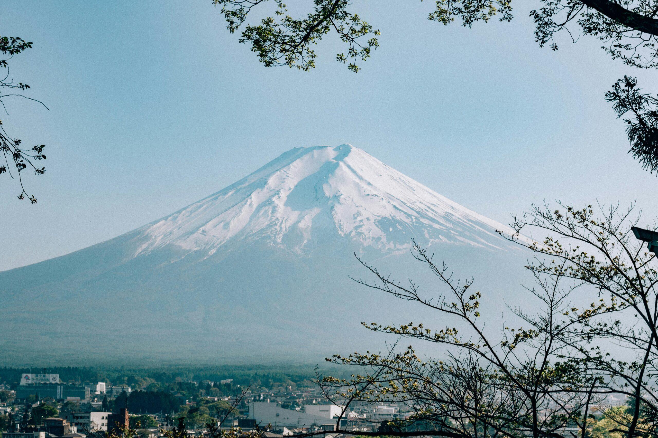 Vue d’un volcan enneigé majestueux dominé par une ville japonaise depuis une colline verdoyante
