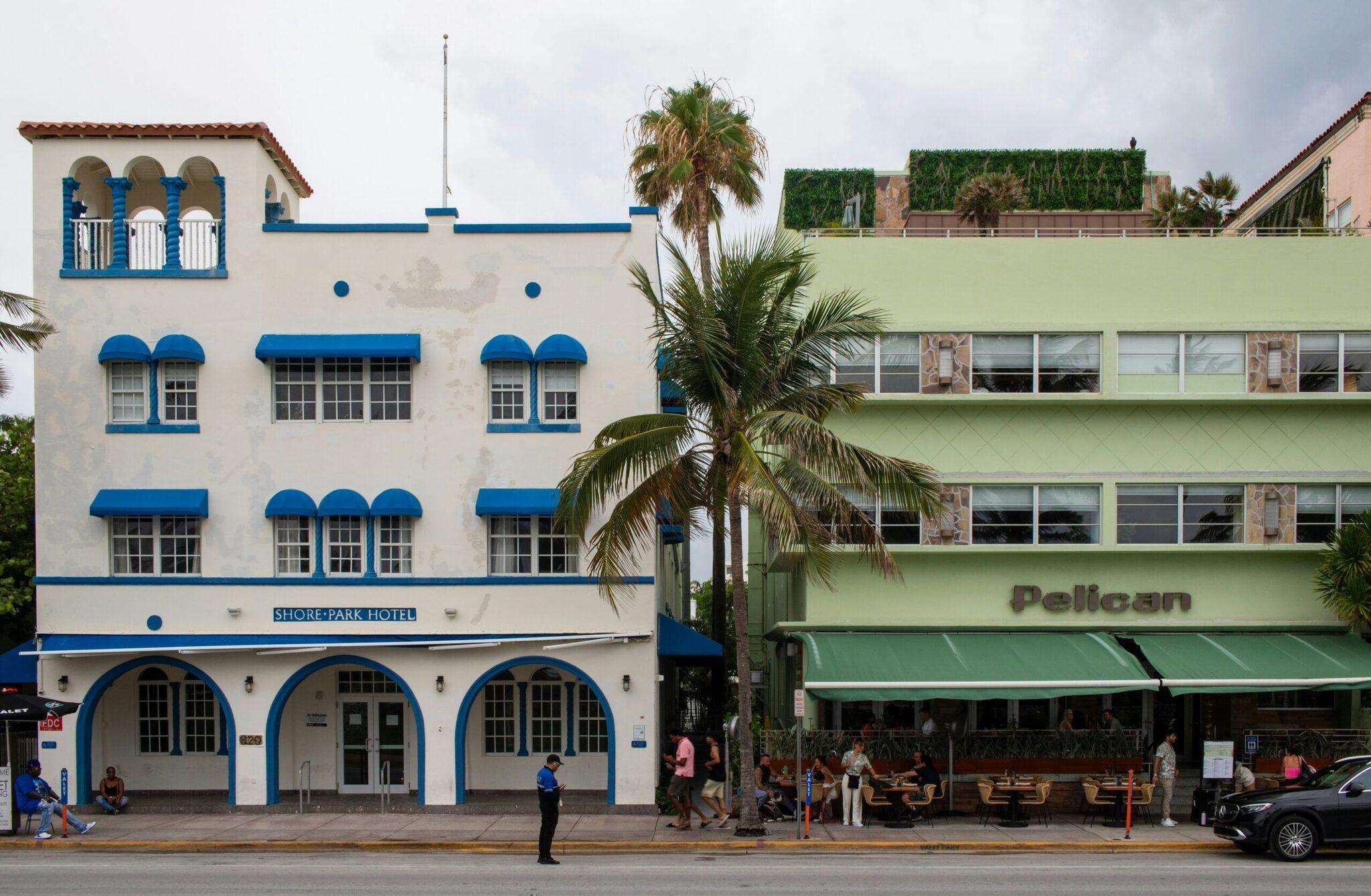 Façades colorées de style Art déco blanc et bleu avec palmiers sur une rue animée de Miami Beach