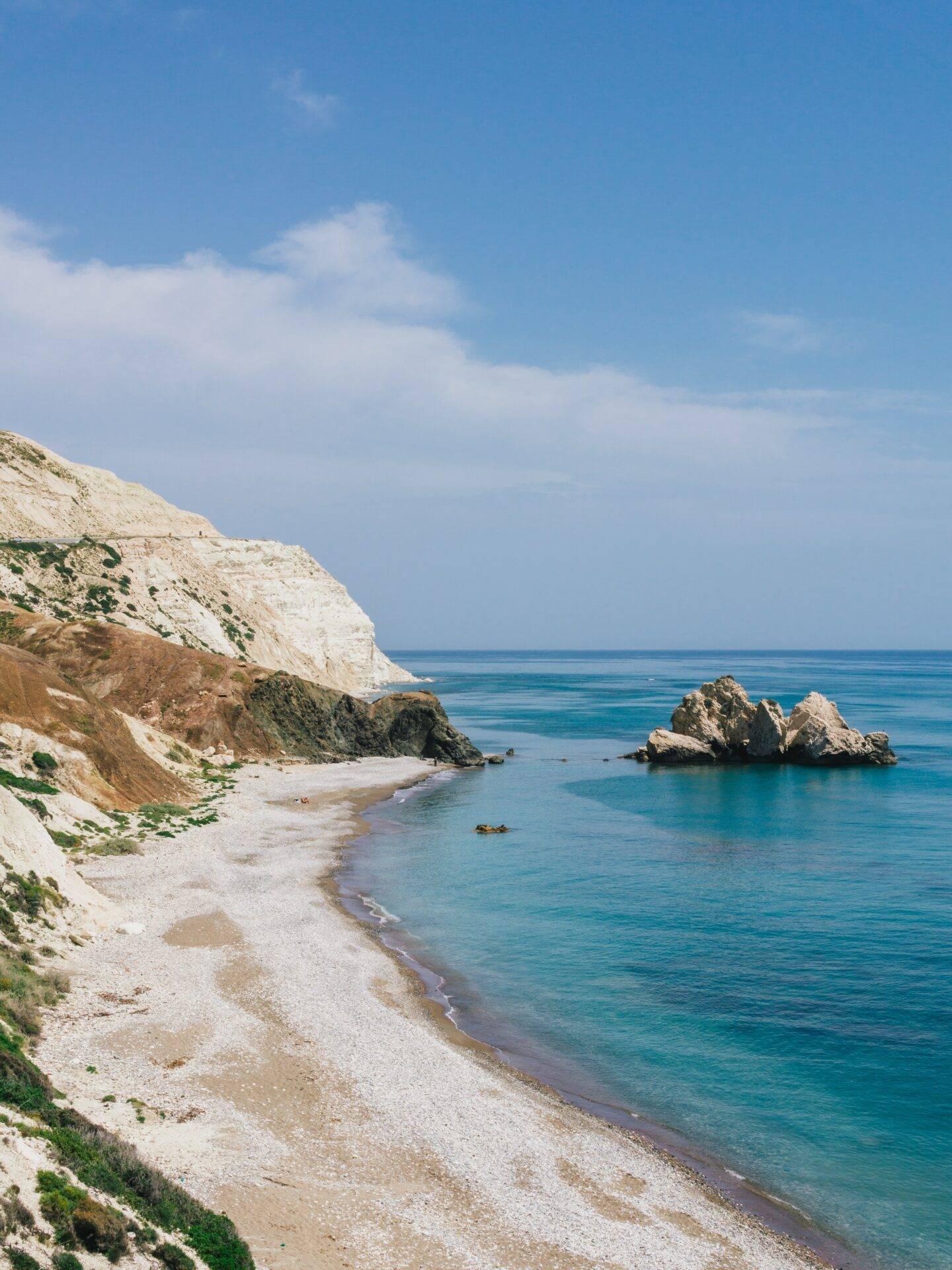 Une plage de galets blanc pur bordée de falaises calcaires face à une mer turquoise méditerranéenne cristalline