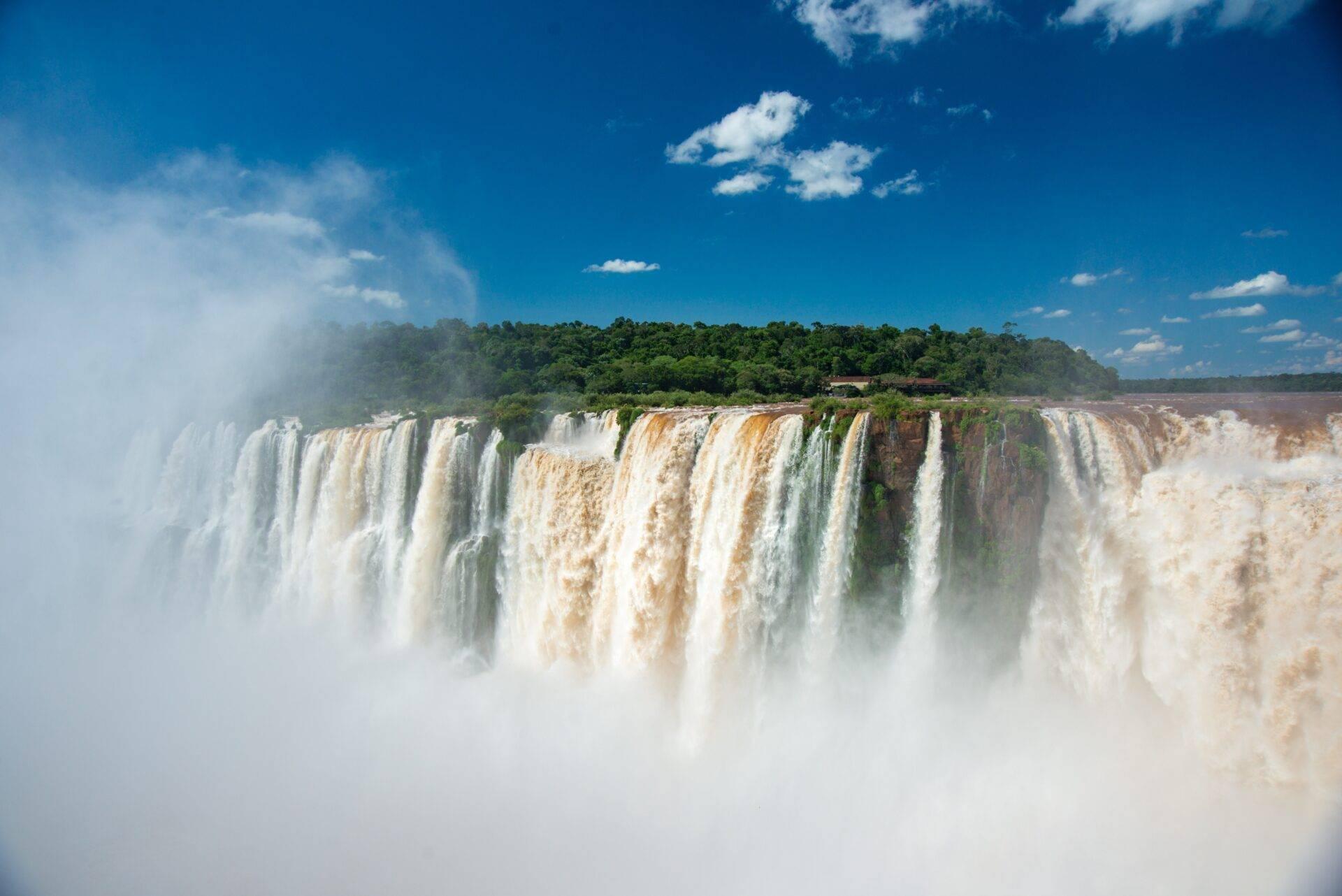 Imposantes chutes d’eau en cascade avec brume blanche épaisse, forêt luxuriante et ciel bleu