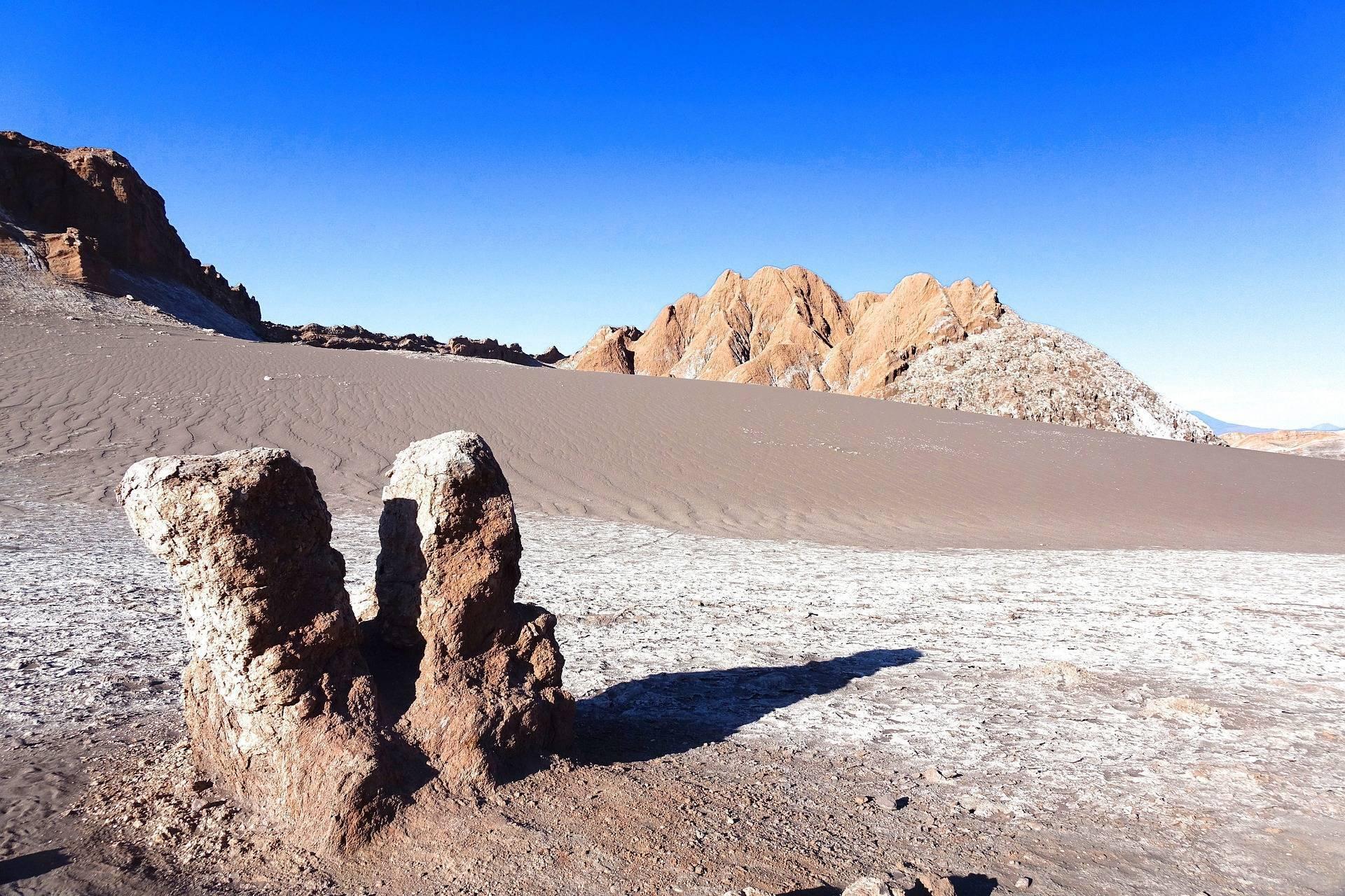 Formation rocheuse distinctive dans un désert aride avec montagnes colorées sous ciel bleu dégagé