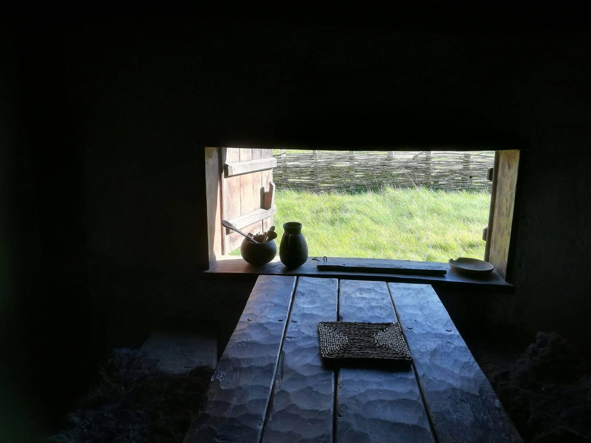 Vue intérieure d’une maison traditionnelle danoise avec table en bois brut et vue sur prairie verte
