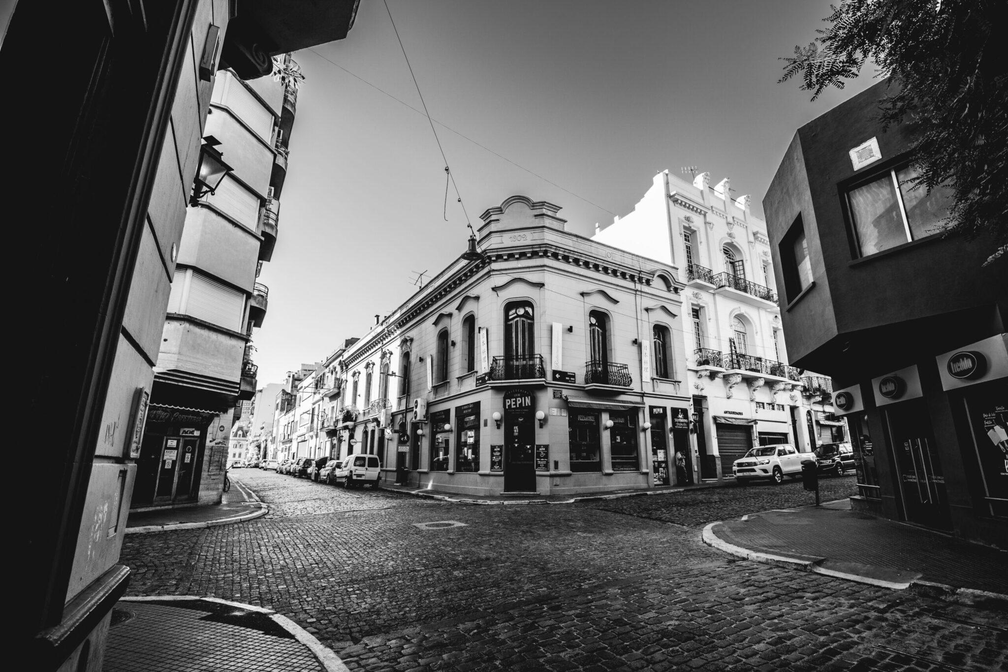Une rue pavée bordée de bâtiments coloniaux blancs avec commerces au rez-de-chaussée dans un quartier historique