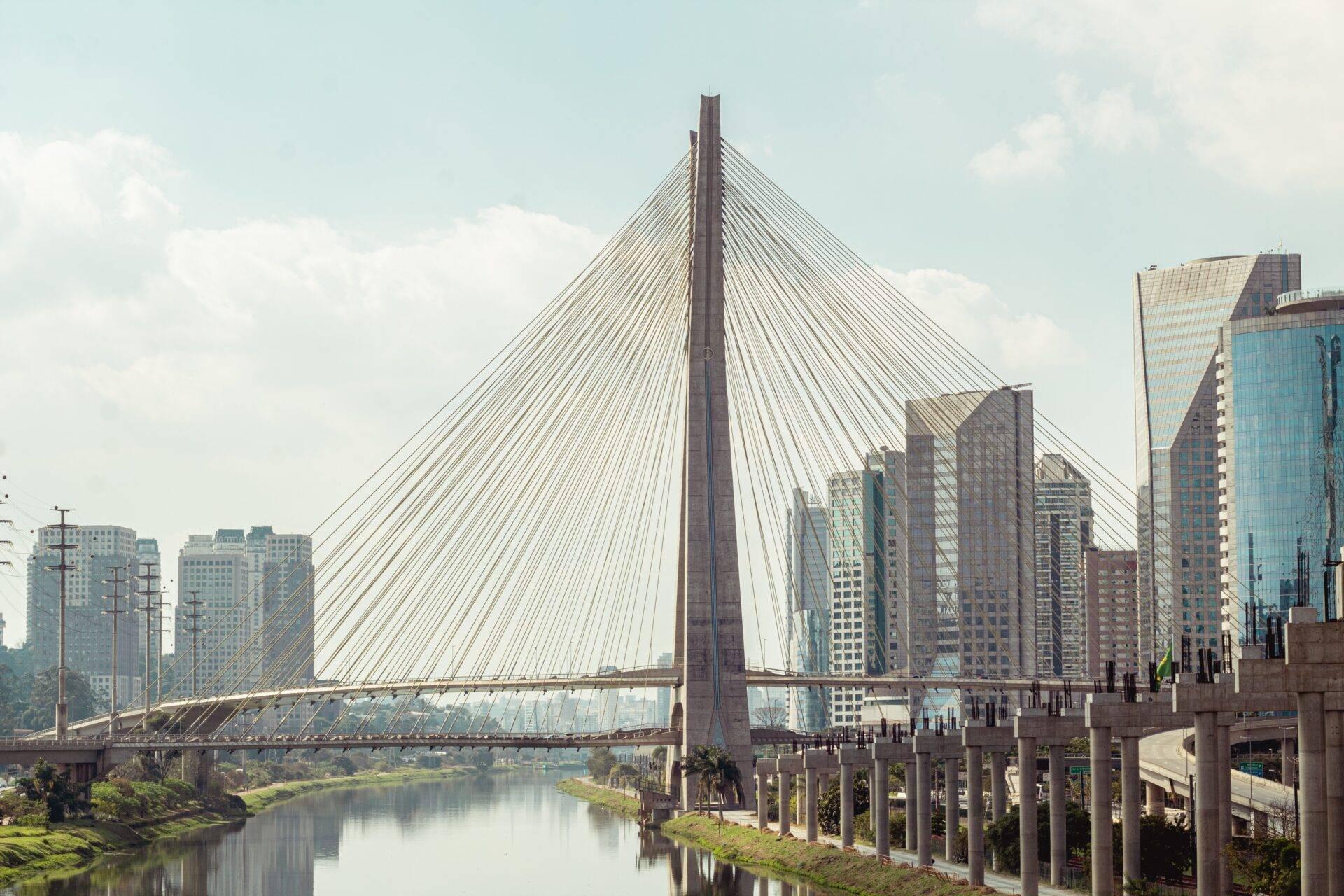Un pont à câbles modernes enjambant une rivière avec des gratte-ciel en arrière-plan sous un ciel dégagé