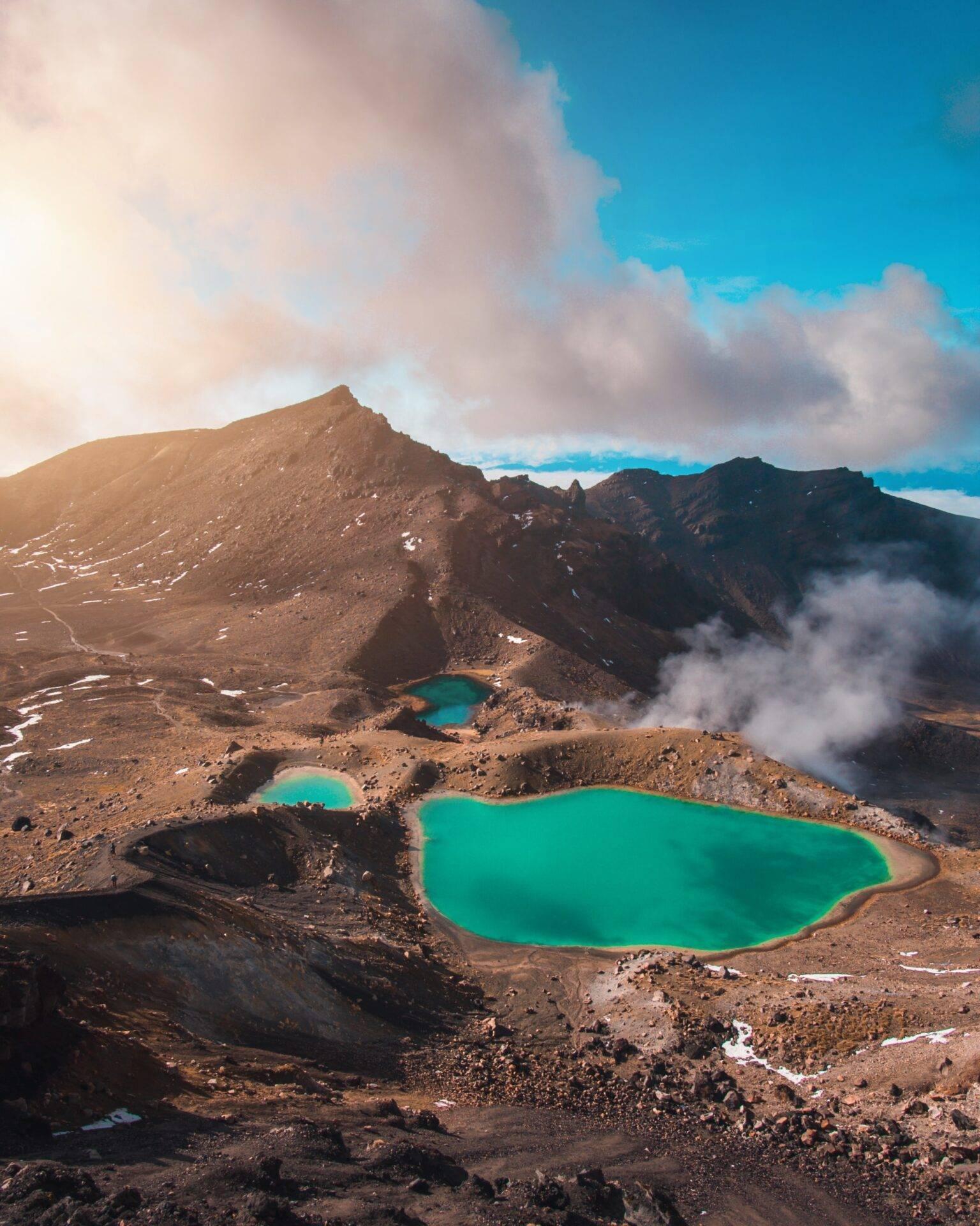Vue aérienne de lacs géothermiques turquoise nichés dans un cratère volcanique entouré de montagnes