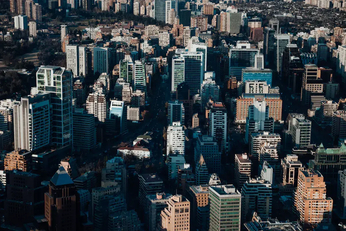 Vue aérienne d’une dense métropole avec immeubles de verre, gratte-ciel et bâtiments résidentiels sous un ciel dégagé