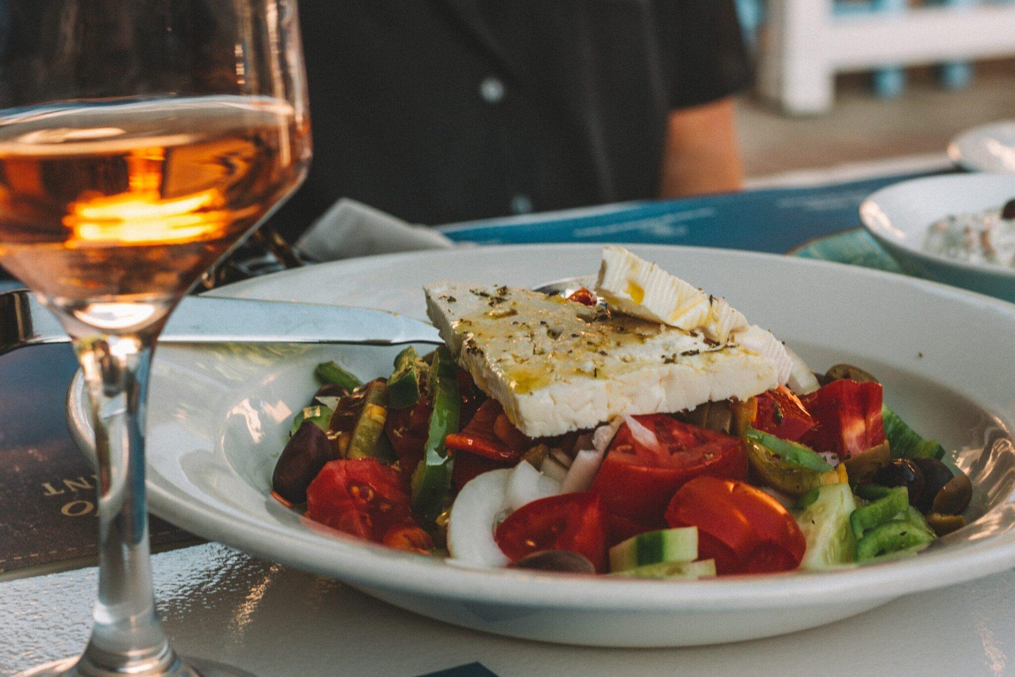 Assiette de salade méditerranéenne avec feta et verre de vin rosé en terrasse ensoleillée