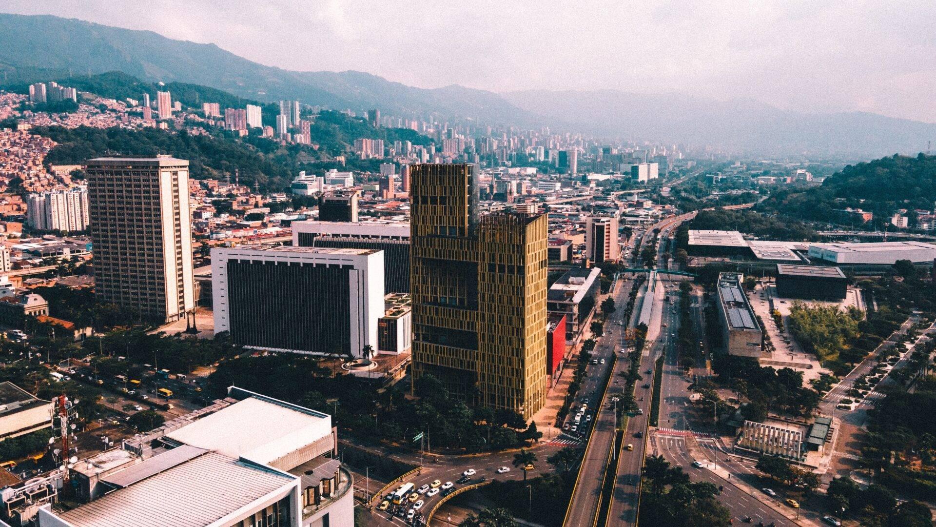 Vue aérienne d’une métropole colombienne avec gratte-ciels modernes, montagnes verdoyantes et dense urbanisation encadrant le centre-ville