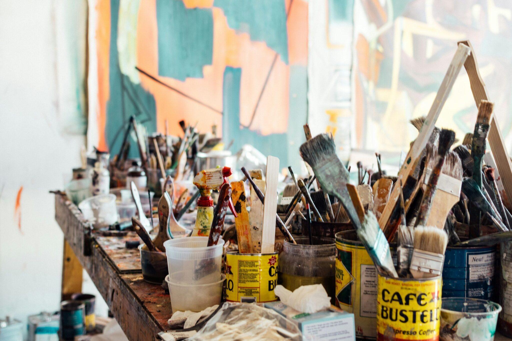 Atelier d’artiste avec pinceaux, pots de peinture et toile colorée en arrière-plan illustrant la scène créative