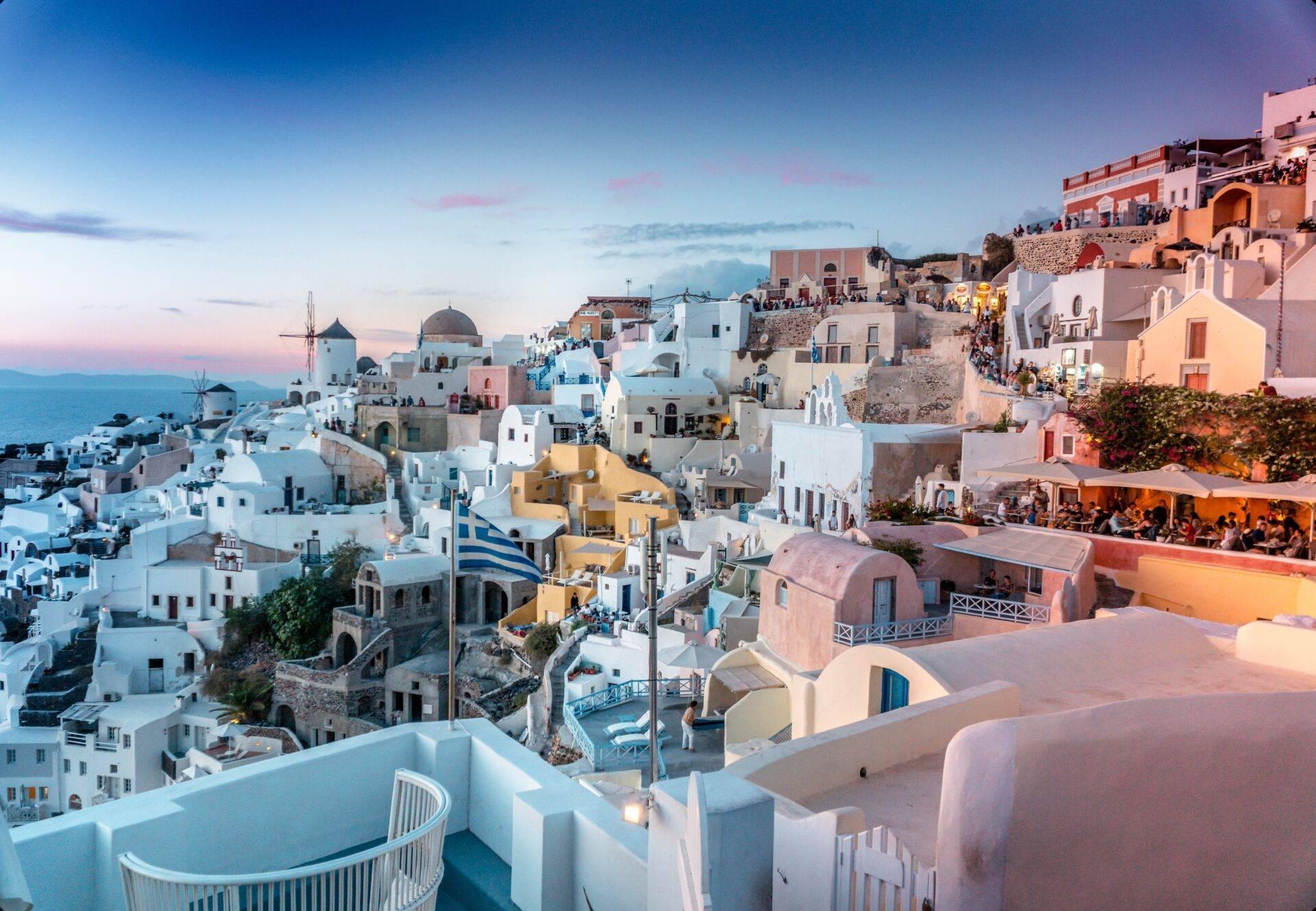 Vue panoramique d’un village blanc et coloré perché sur une falaise méditerranéenne au coucher de soleil