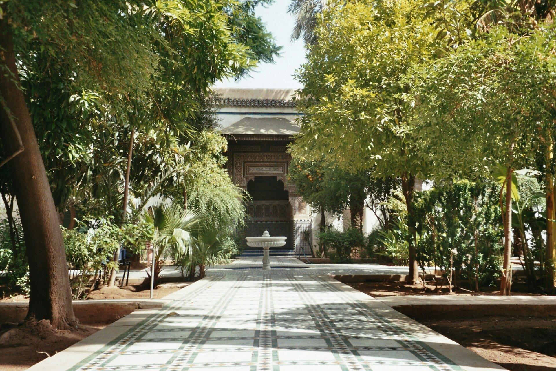 Allée ombragée d’un palais marocain avec fontaine centrale et architecture traditionnelle ornementée