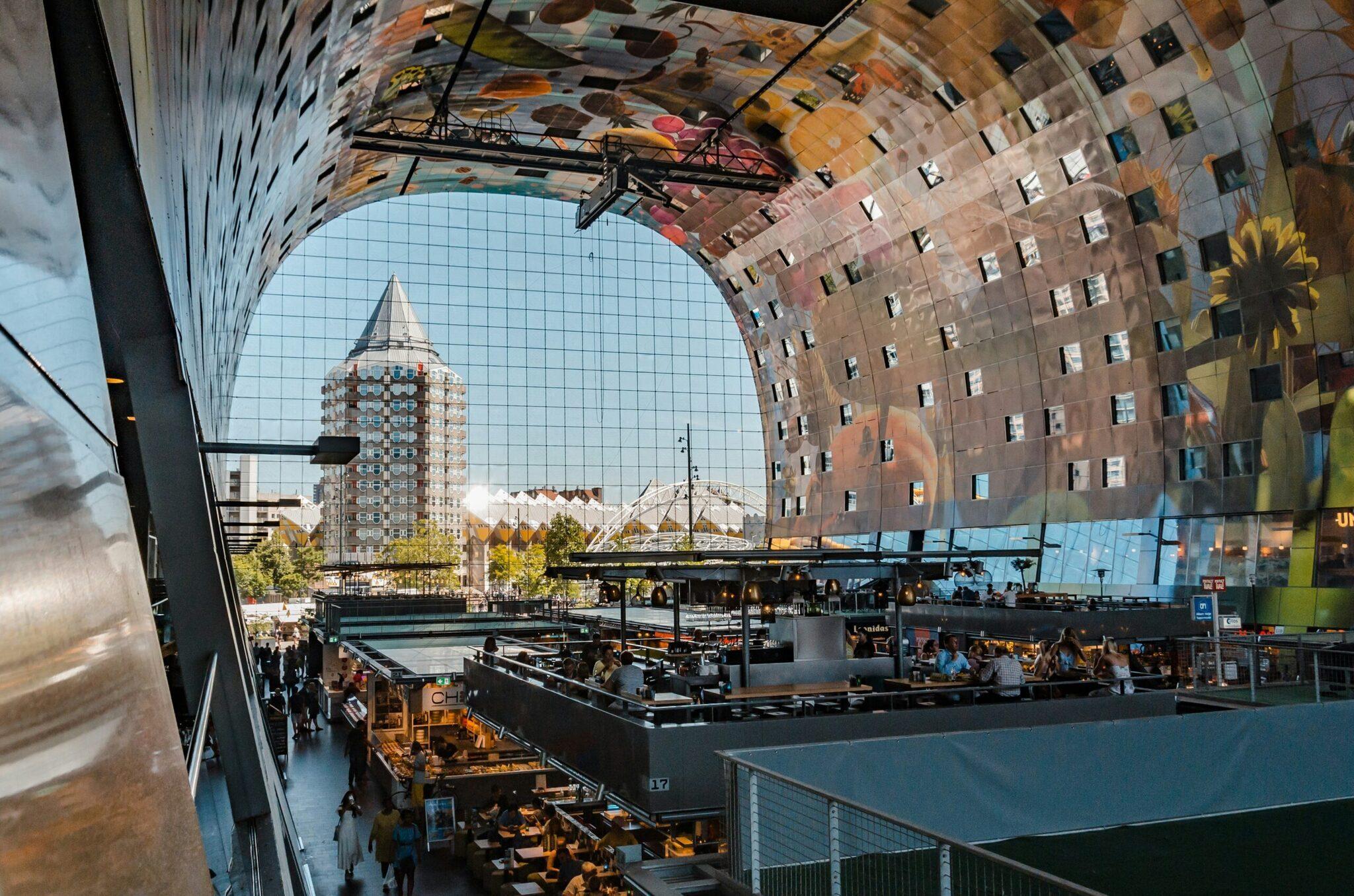 Vue depuis l’intérieur d’un bâtiment moderne sur une place publique animée avec architecture contemporaine et bâtiments résidentiels