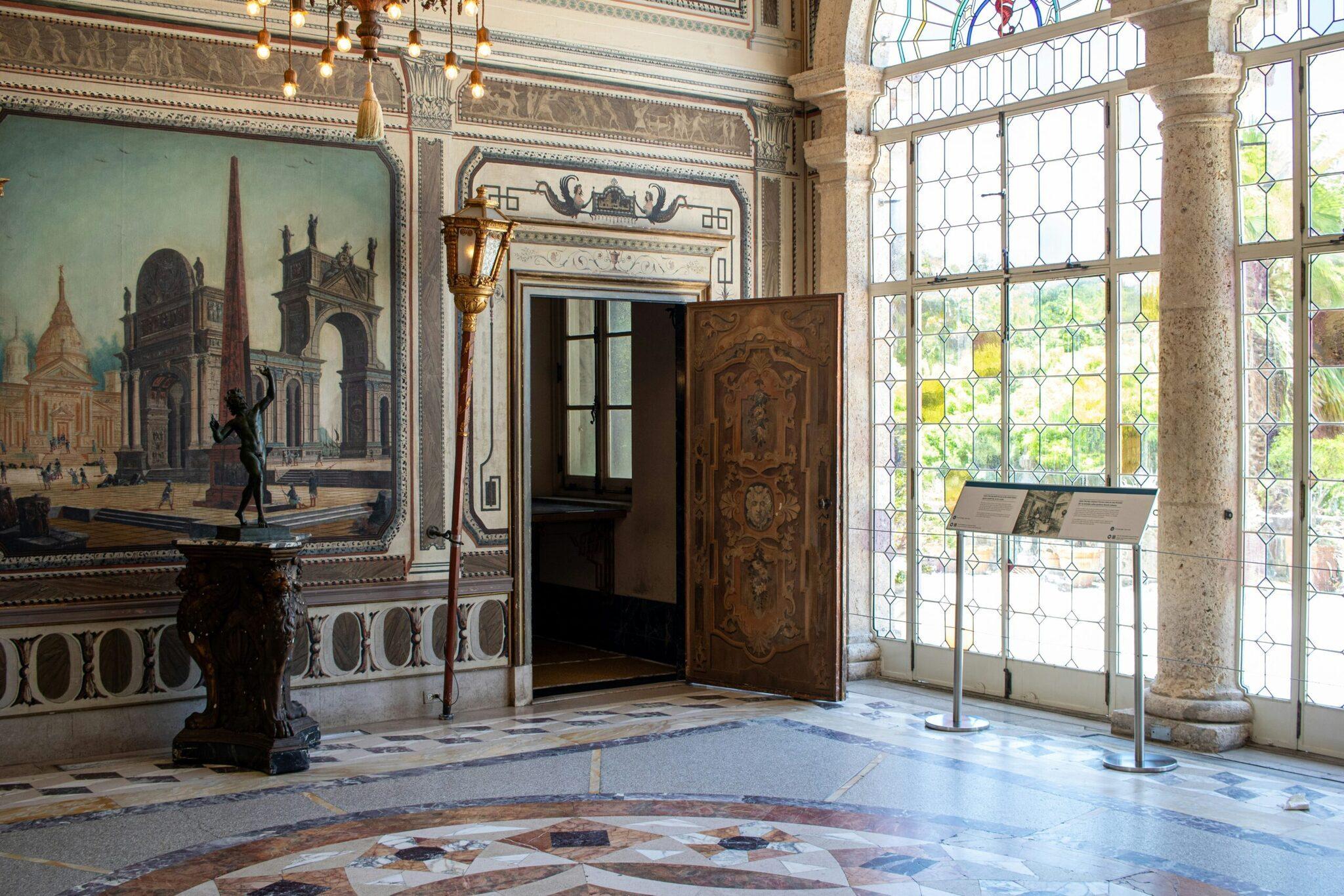 Intérieur élégant d’un palais avec fresques murales, colonnes de marbre et grandes fenêtres à vitraux géométriques