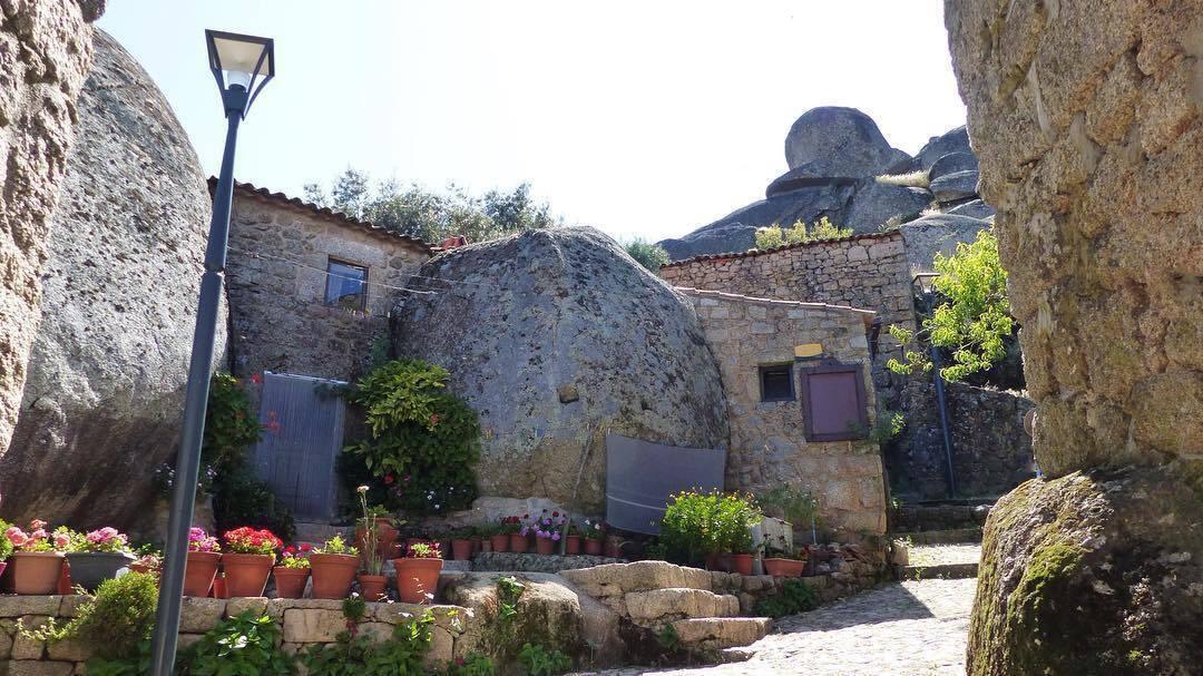 Cour pittoresque entourée de murs en pierre anciens avec pots de fleurs colorés et lampadaire